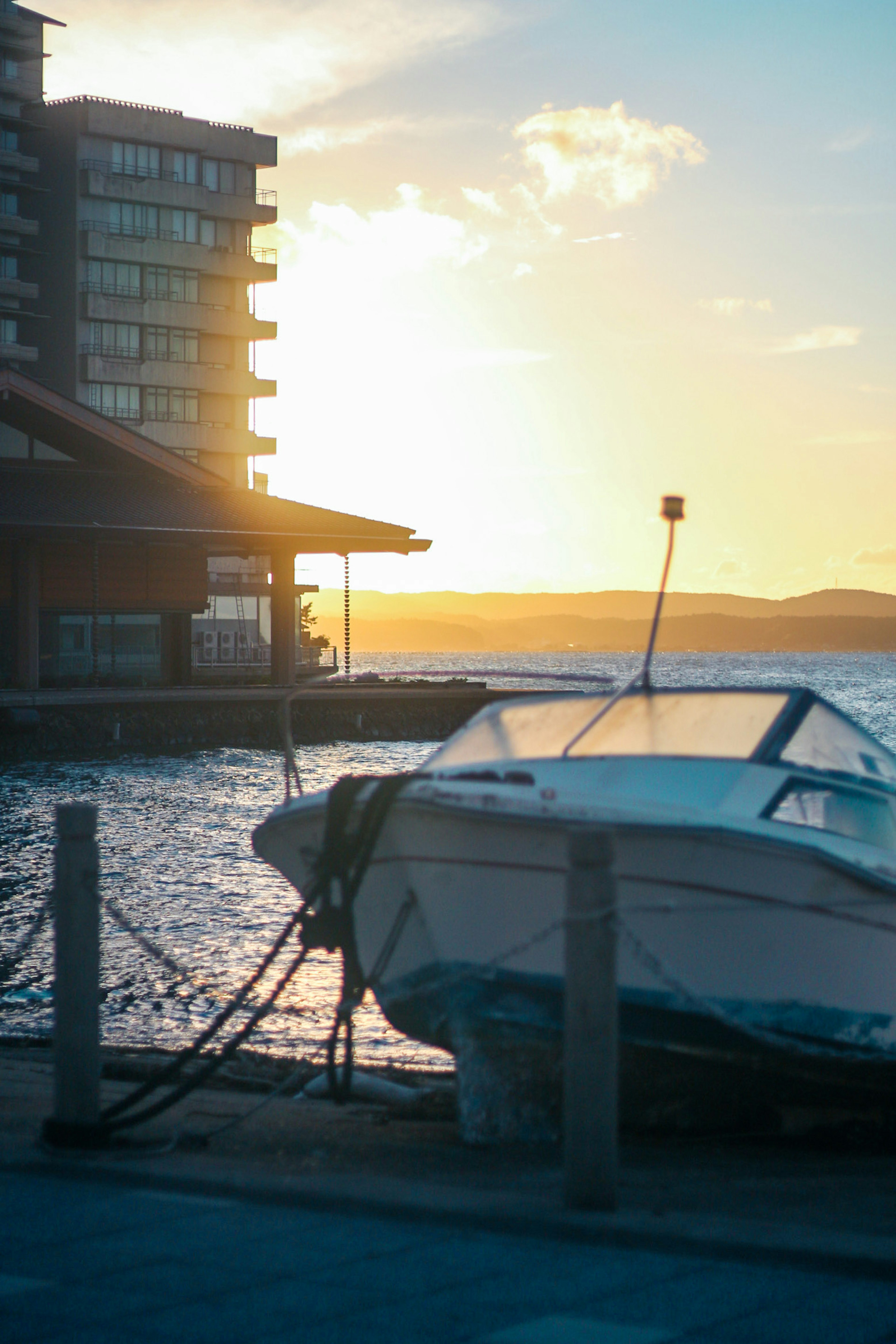 Ein Boot im Hafen mit einem Sonnenuntergang und Hochhäusern im Hintergrund