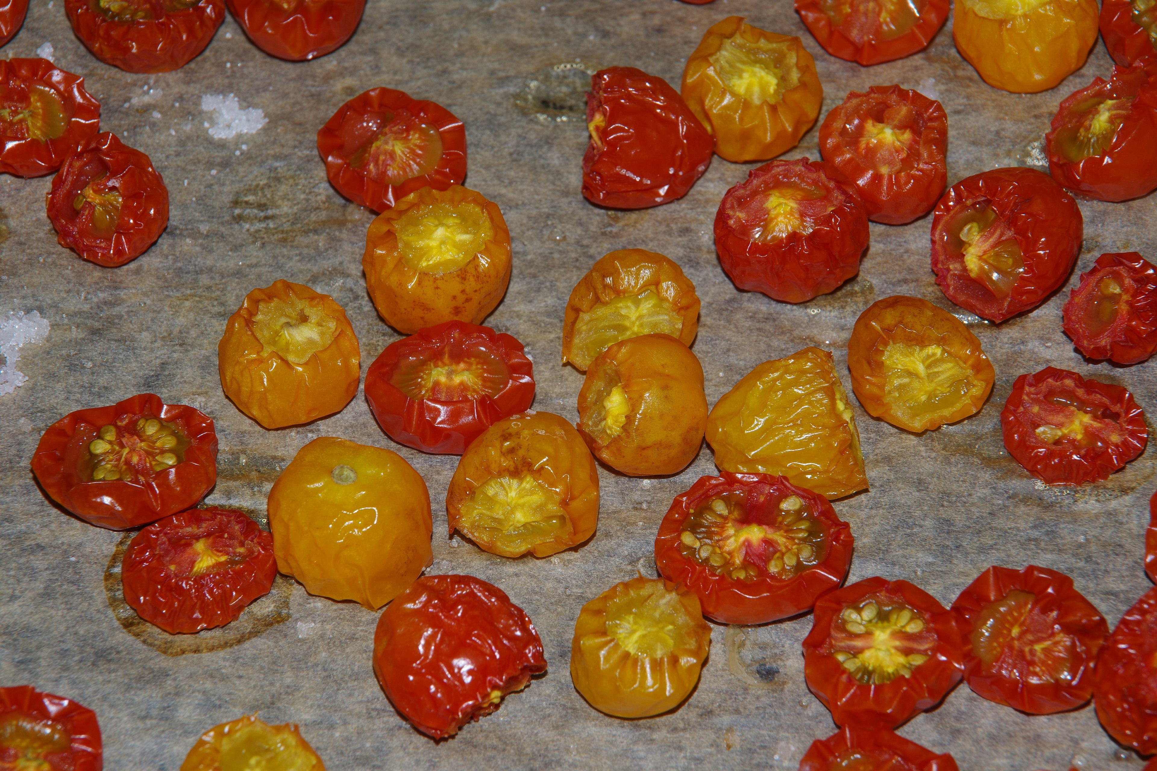 A variety of dried tomatoes in different colors scattered on a surface