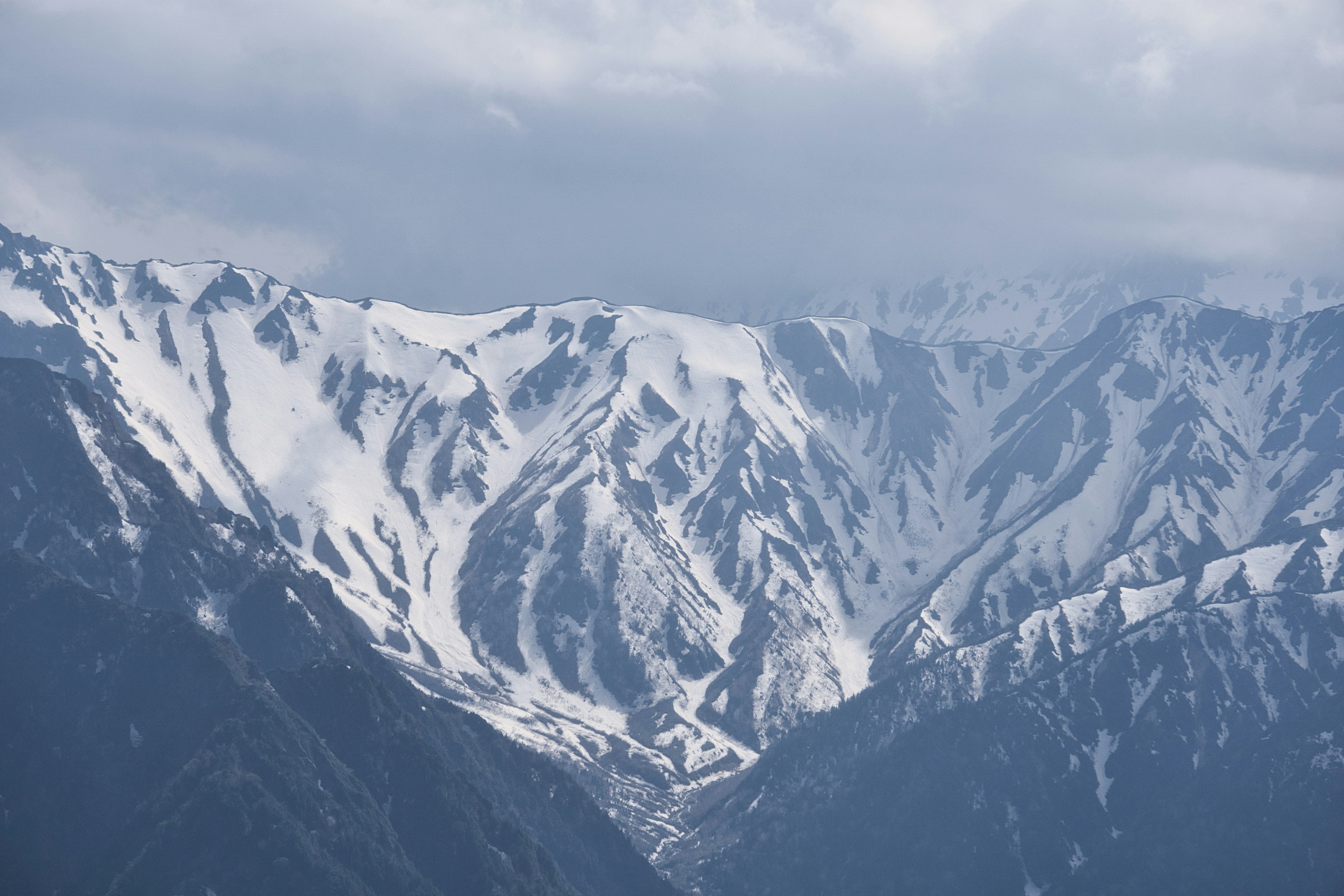 Snow-covered mountain range with cloudy sky