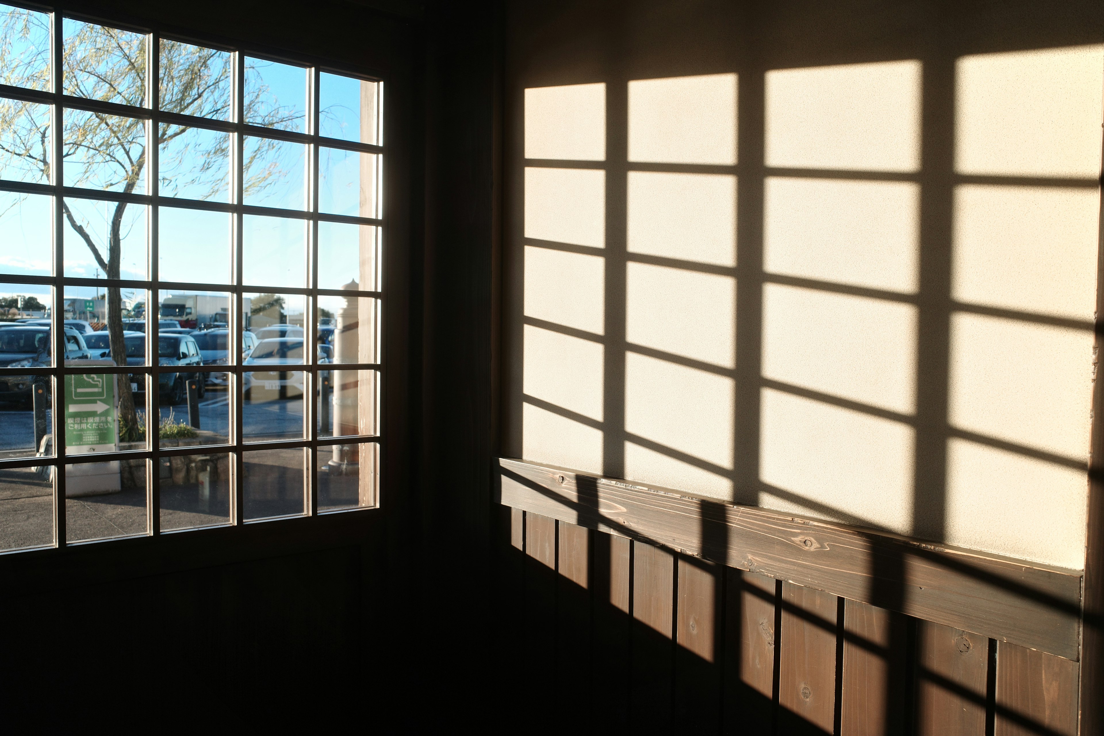 Interior de una habitación con luces y sombras cruzadas desde una ventana