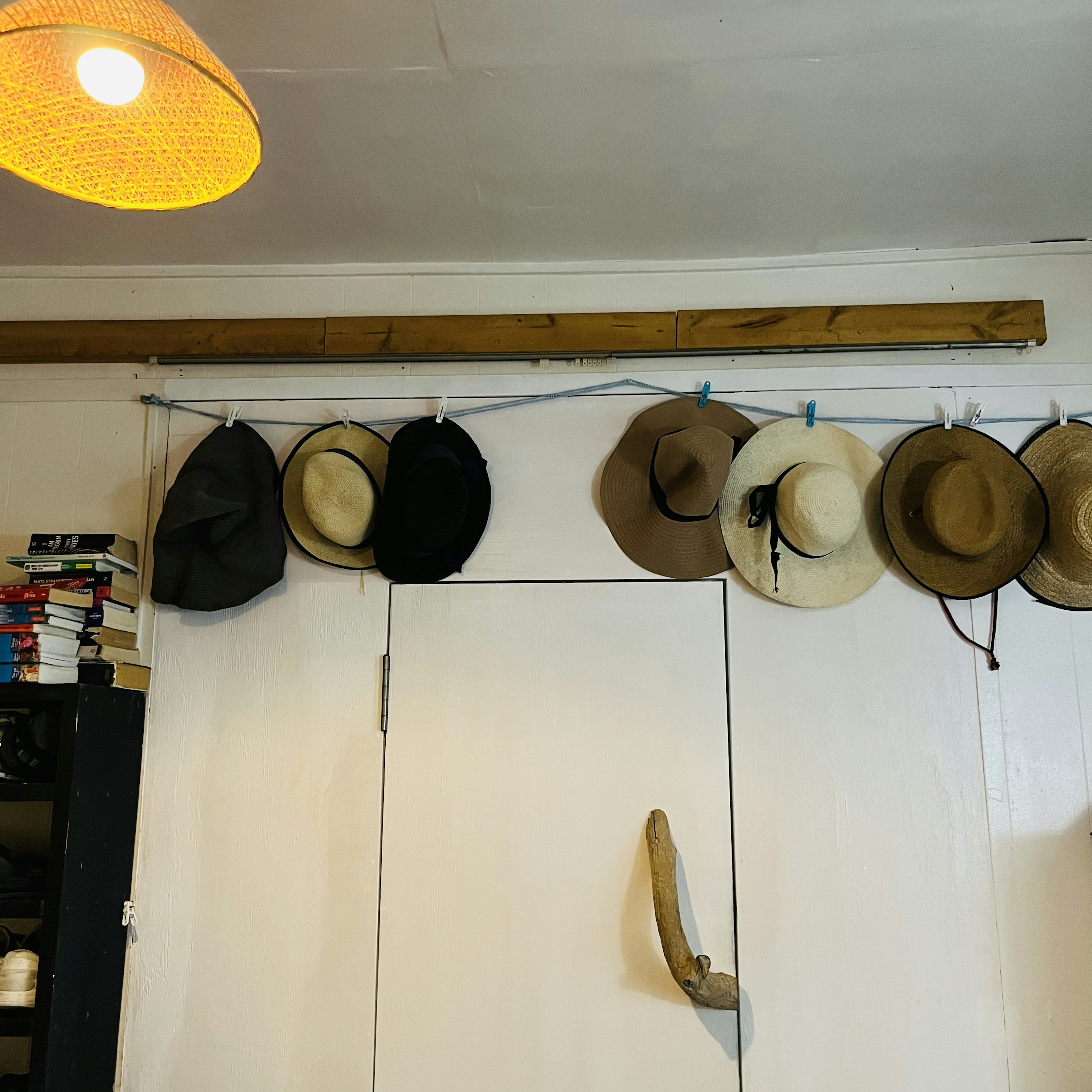 A corner of a room with a white wall and a wooden rod holding various hats