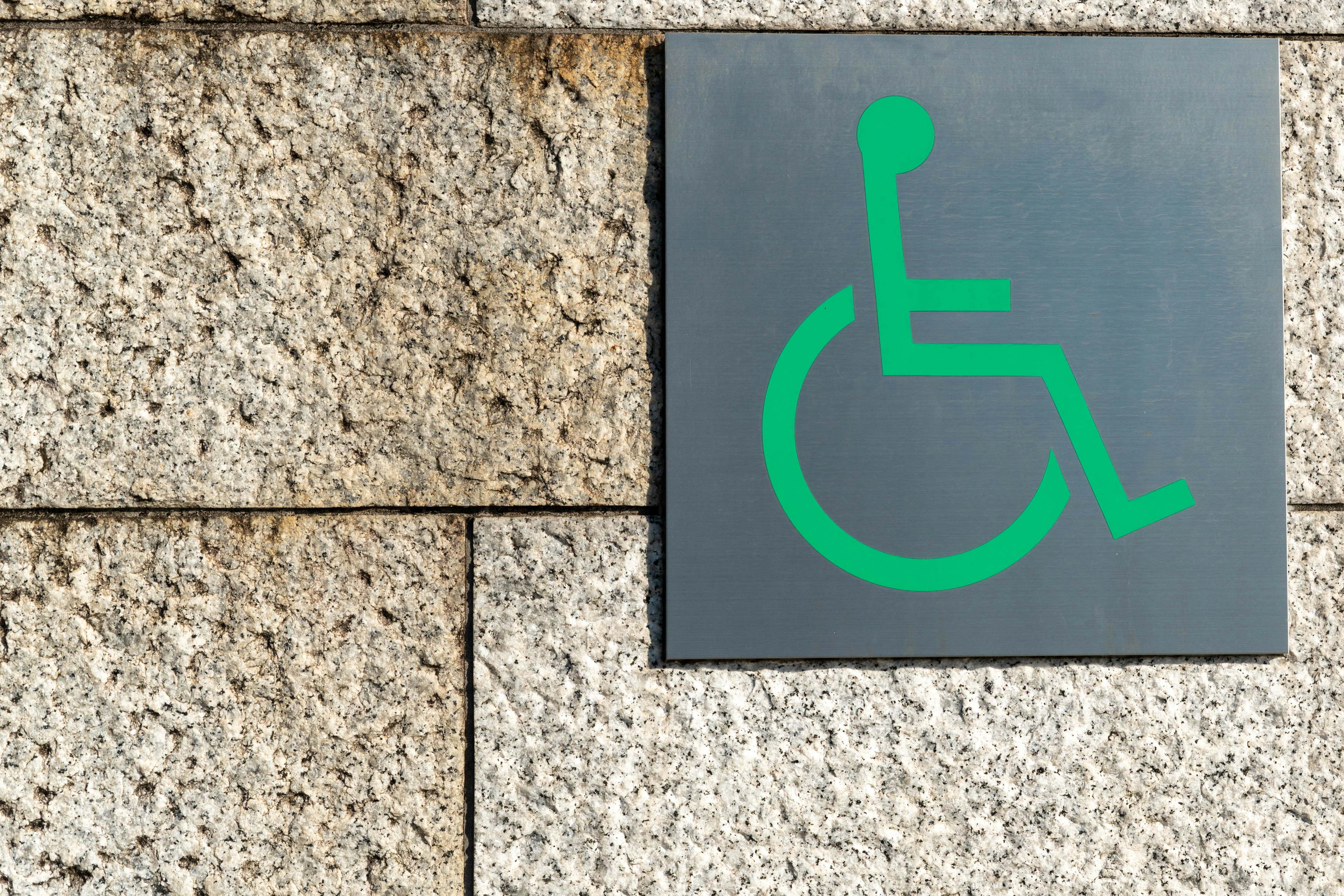 Green wheelchair accessibility symbol on a stone wall