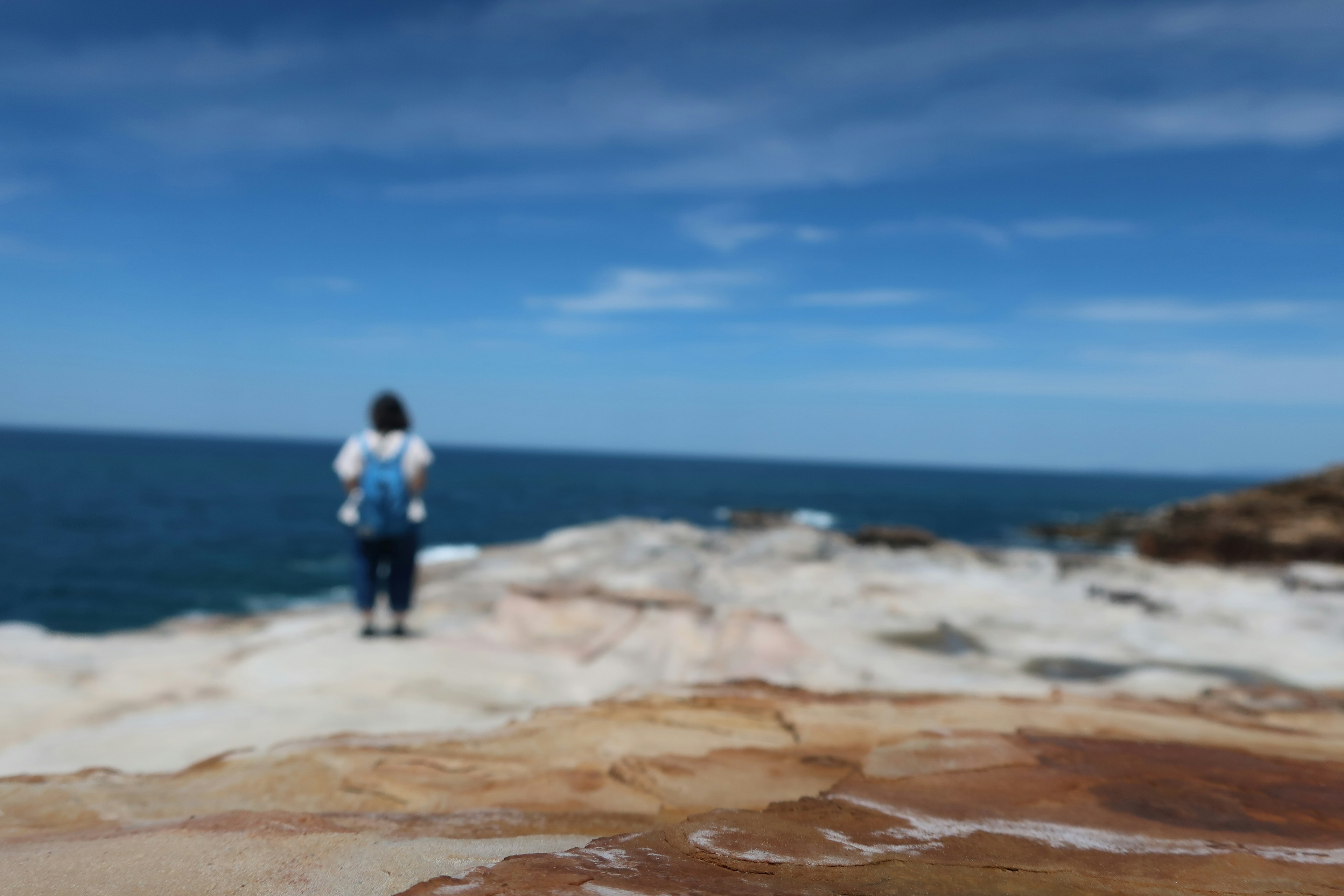 海の景色を背にした人物が立っている岩場