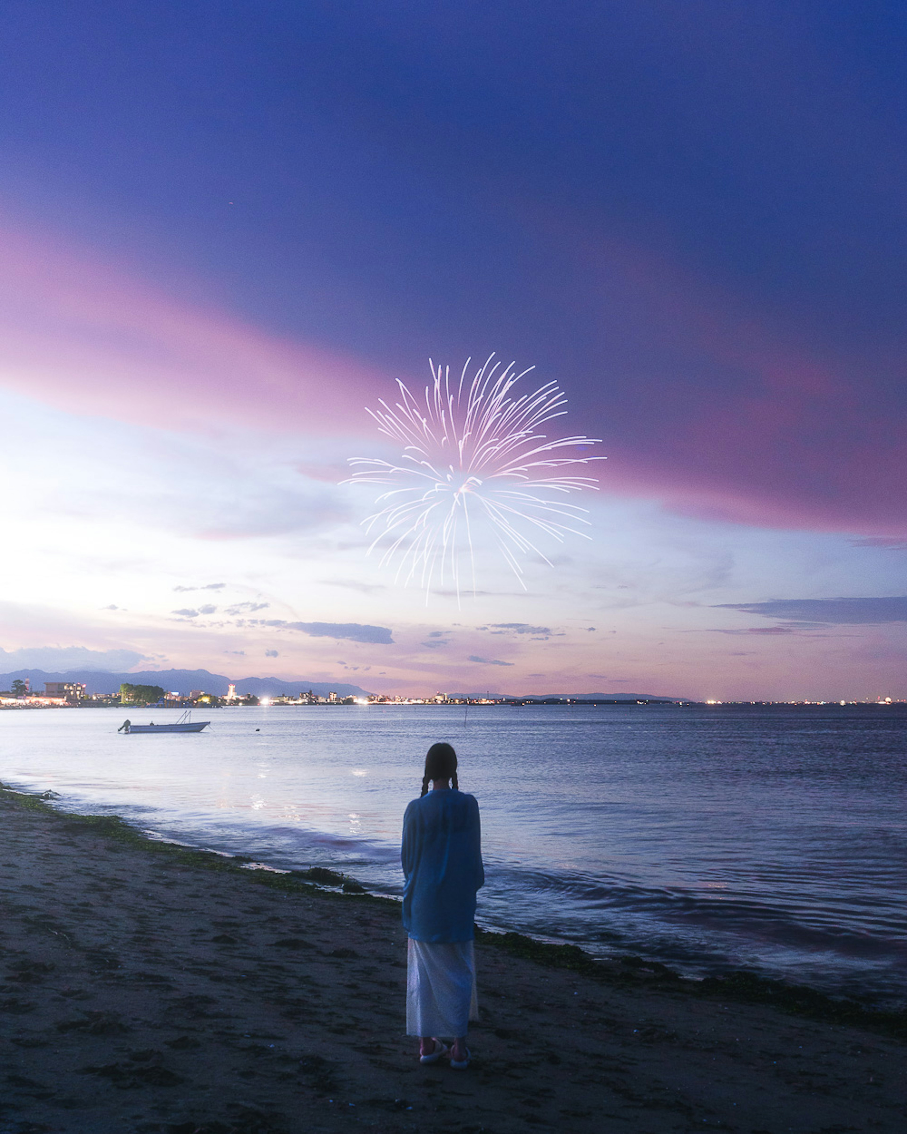 Woman watching fireworks by the beach during sunset