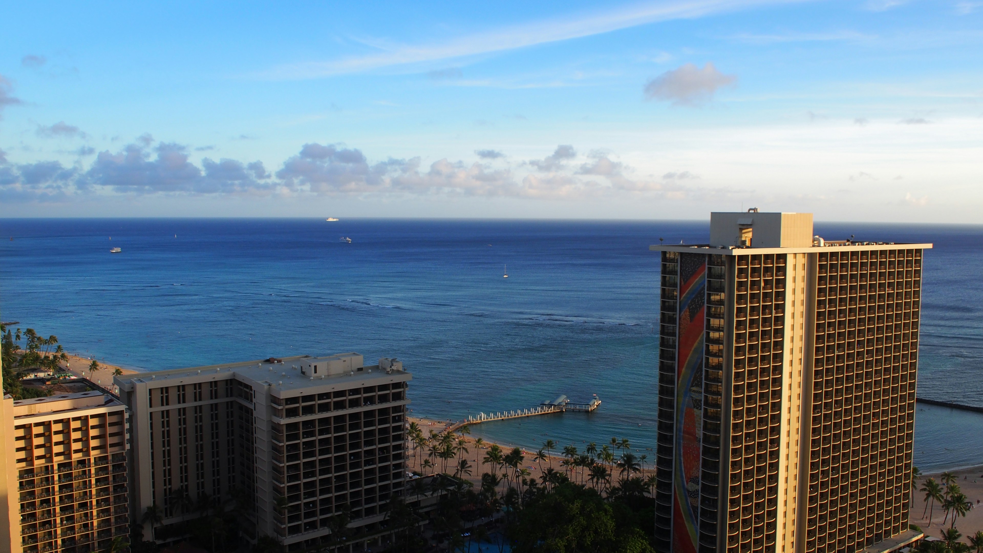 Pemandangan laut biru dan langit dengan gedung tinggi di sepanjang pantai Honolulu