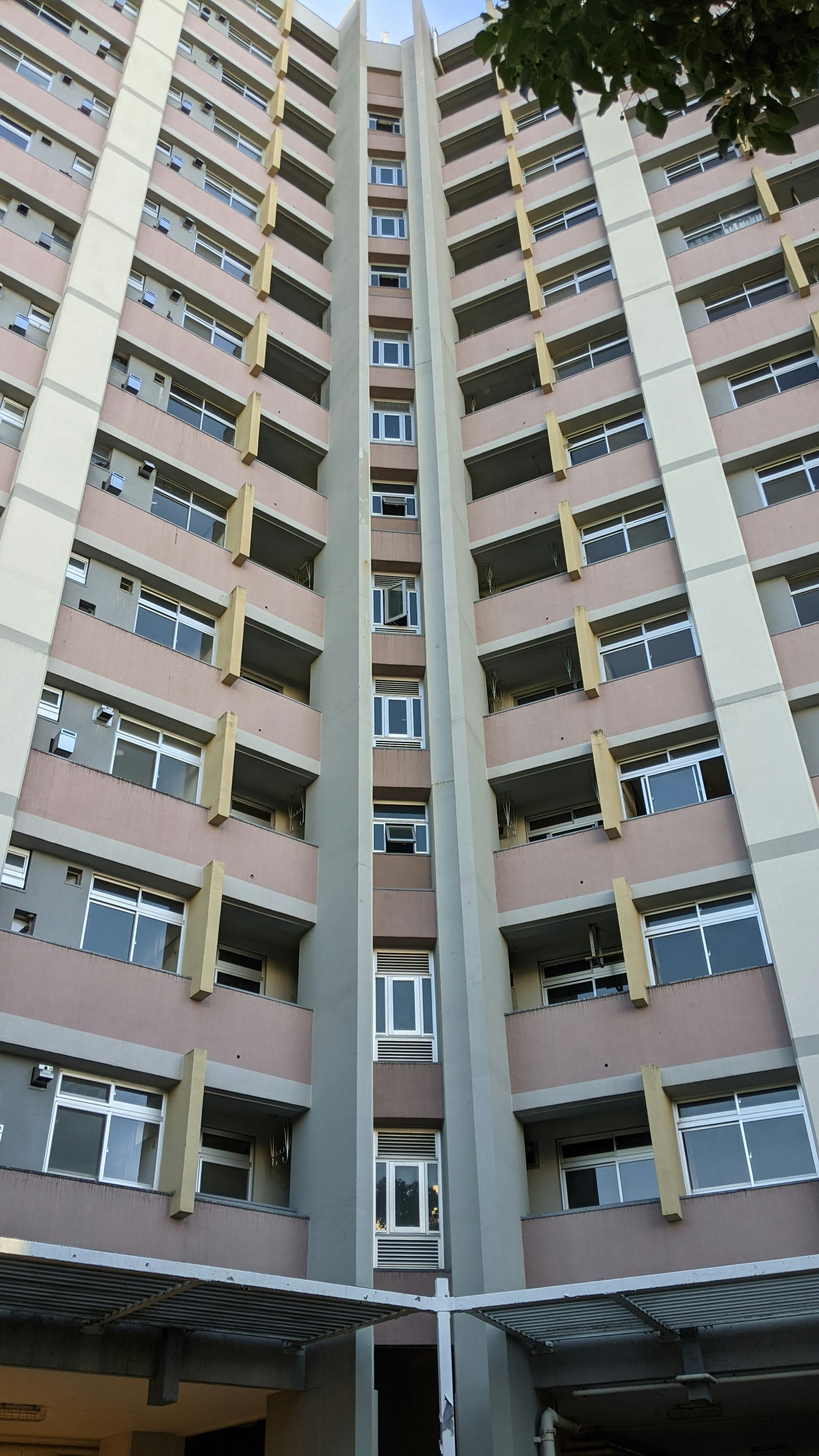 Vista exterior de un edificio de apartamentos de gran altura con un patrón de ventanas en beige y gris