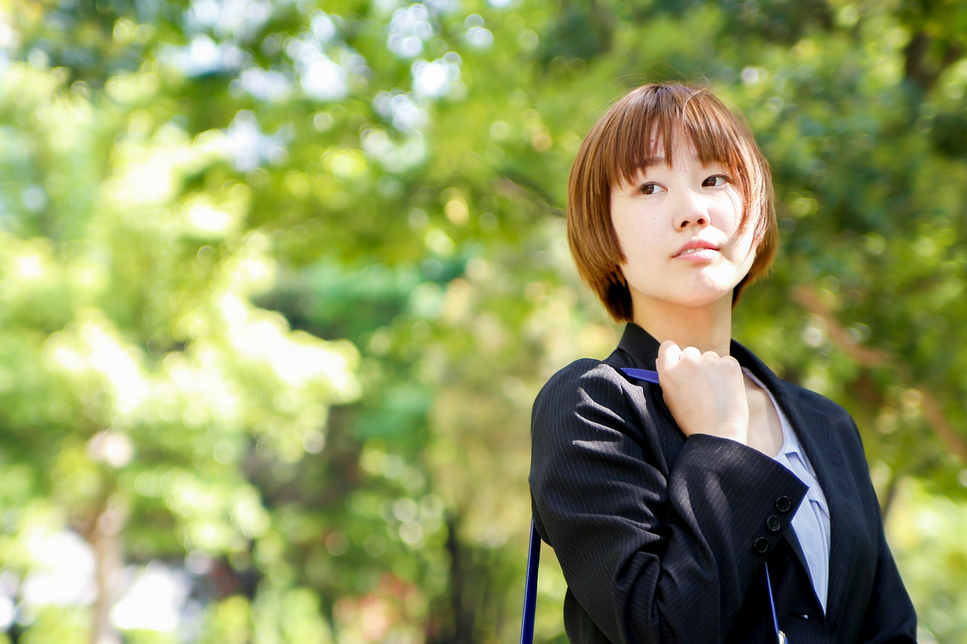 公園中思考的女性 綠色背景 短髮 穿著黑色夾克