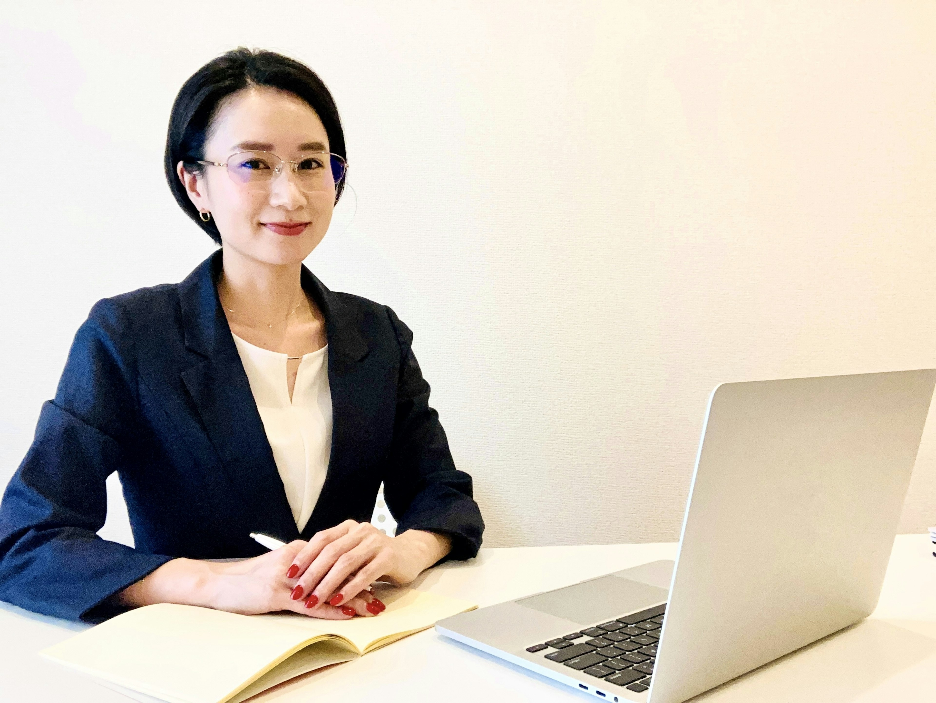 A woman in a business suit sitting at a desk with a laptop