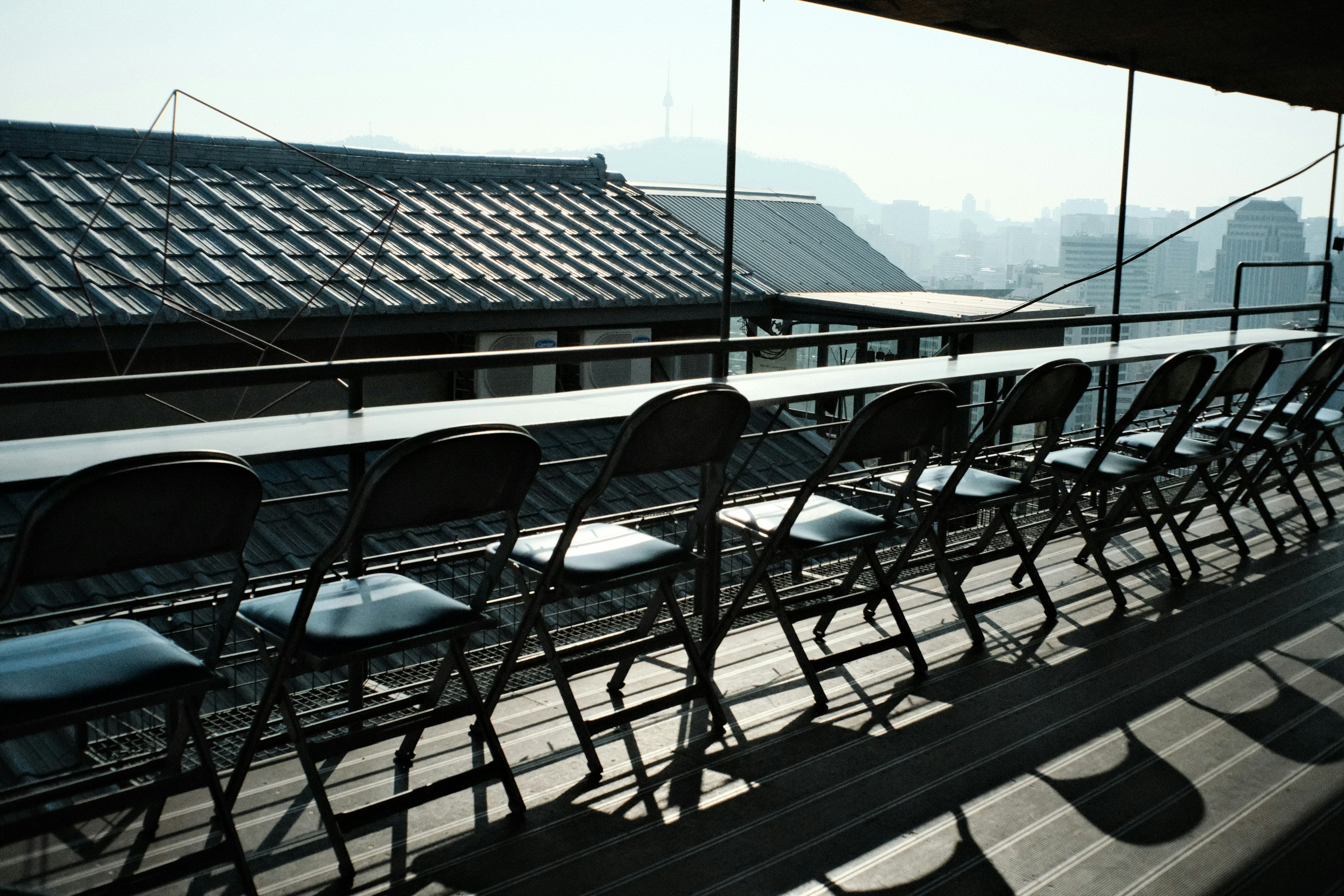 屋根の上に並ぶ黒い椅子が見える風景