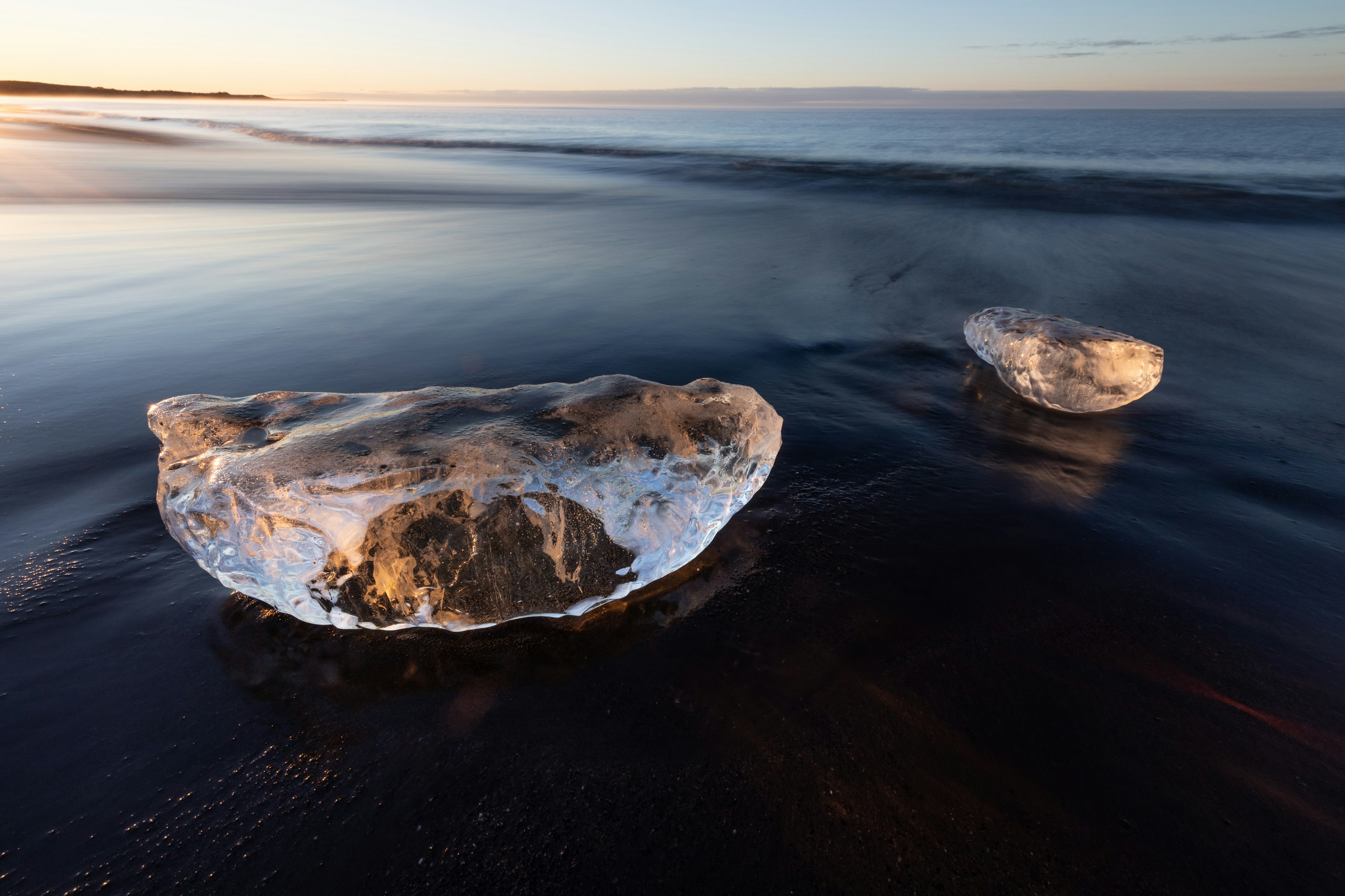 Transparente Eisstücke am Strand bei Sonnenuntergang