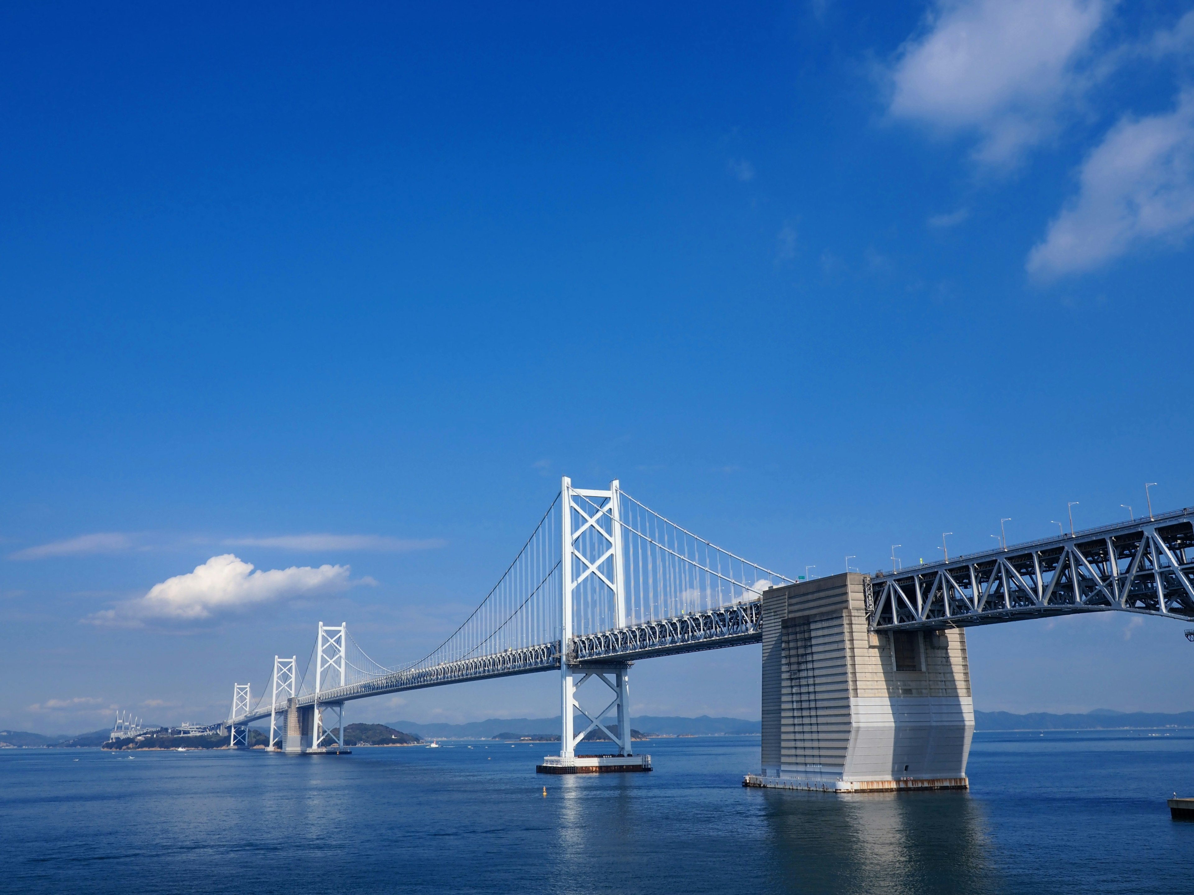 Pemandangan jembatan di bawah langit biru dengan air di sekitarnya