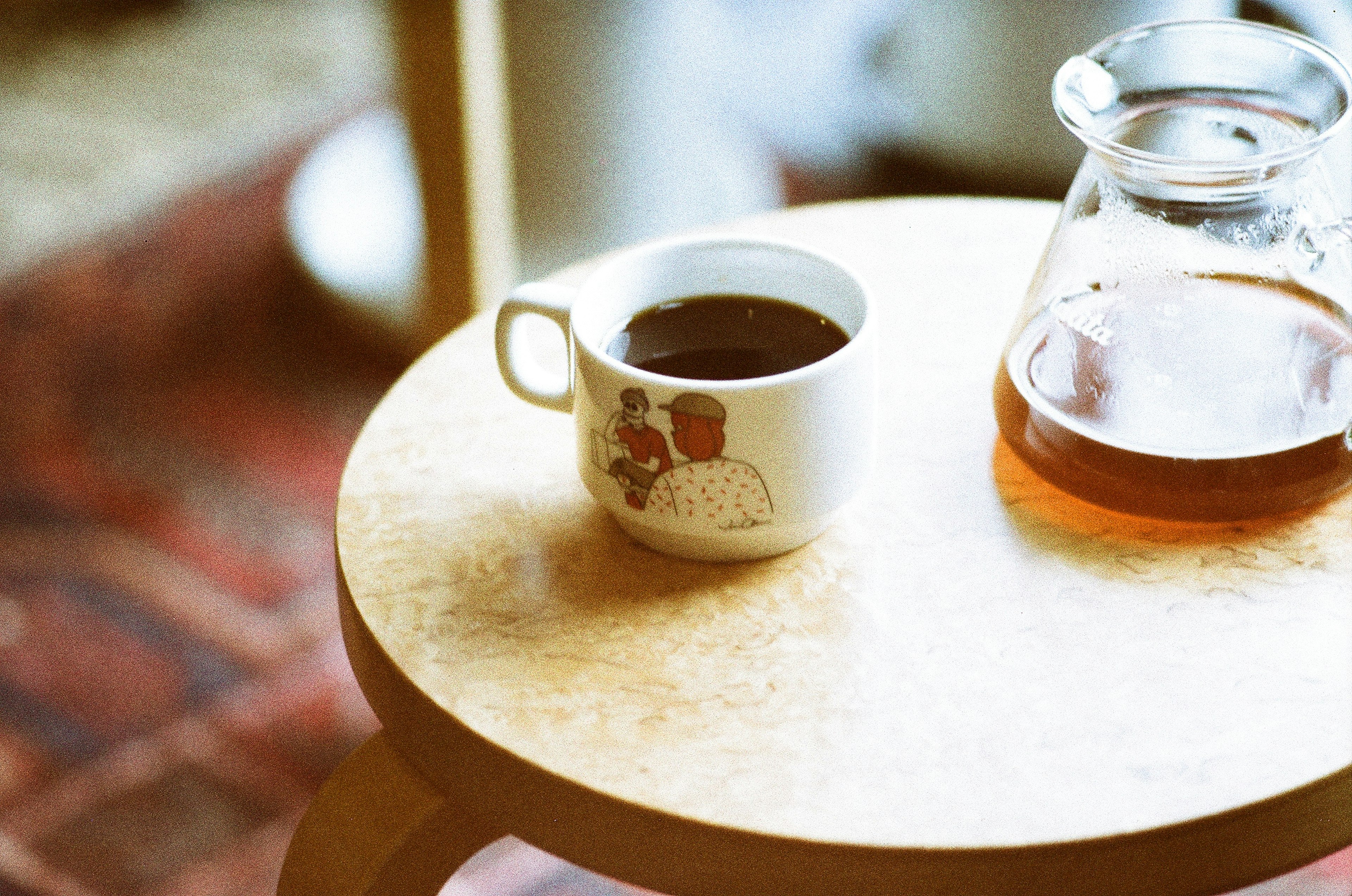 A coffee cup and a carafe on a wooden table