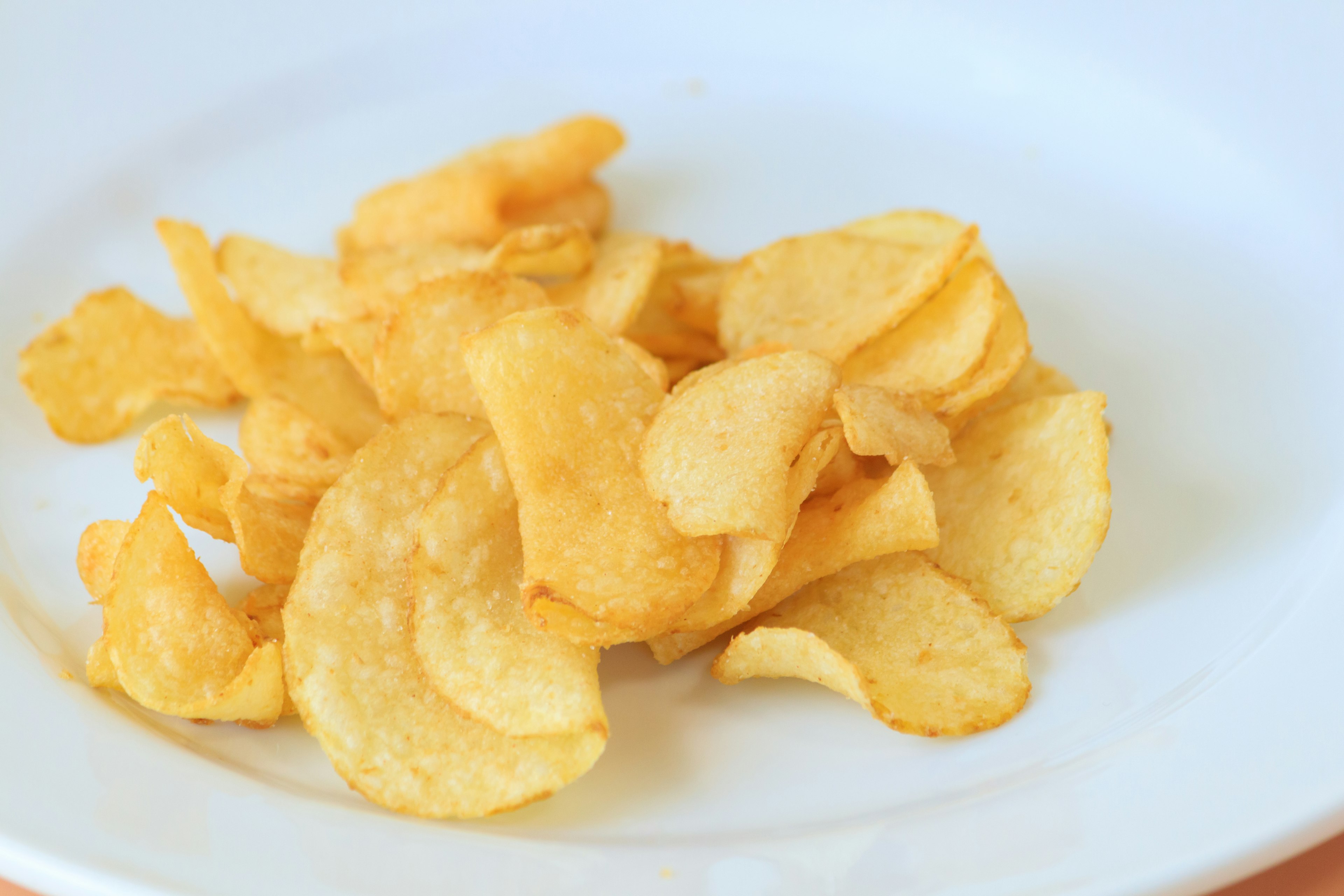 Ein Haufen knuspriger Kartoffelchips auf einem weißen Teller