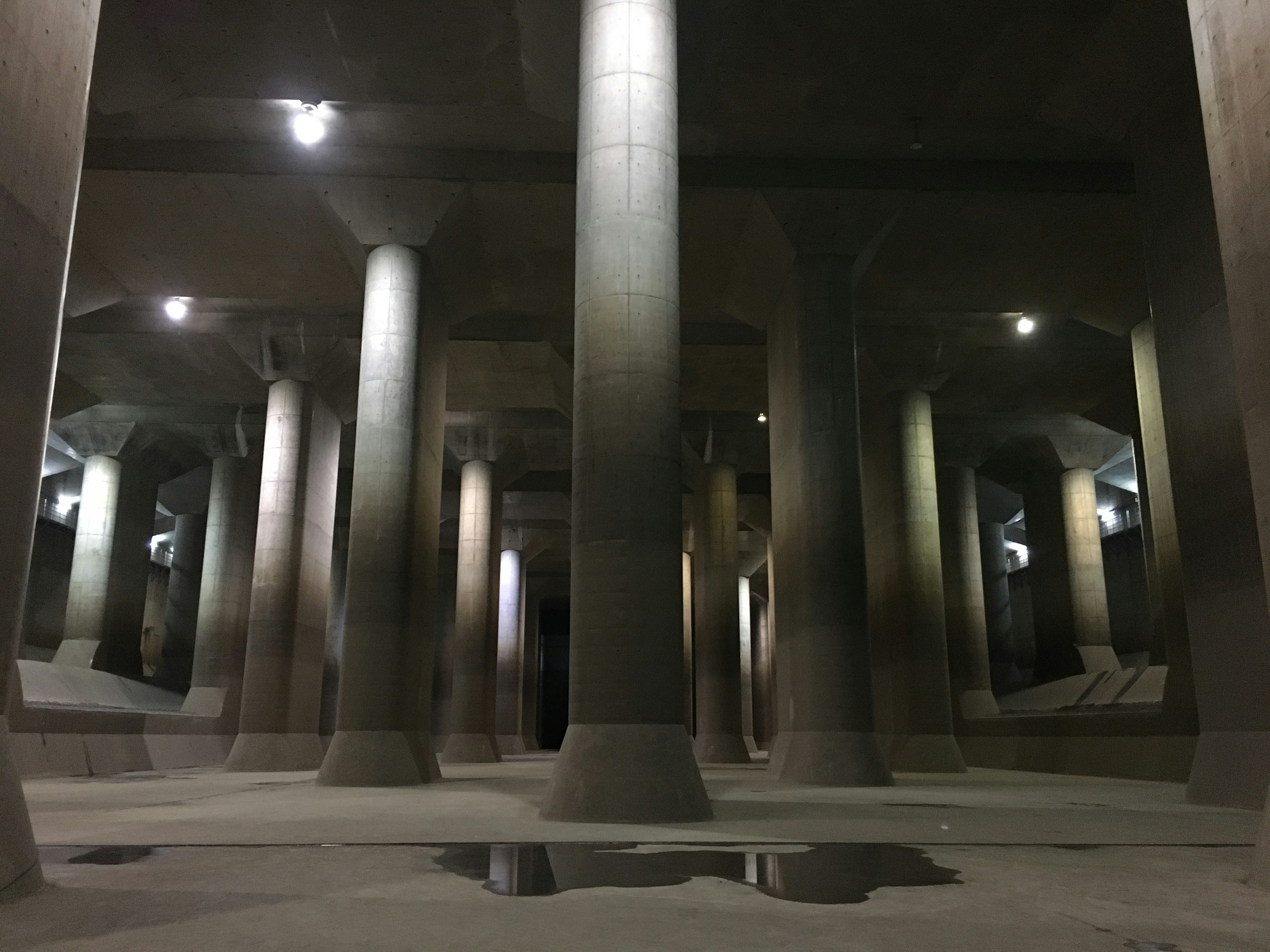 Espace souterrain sombre avec des colonnes en béton et un éclairage ambiant