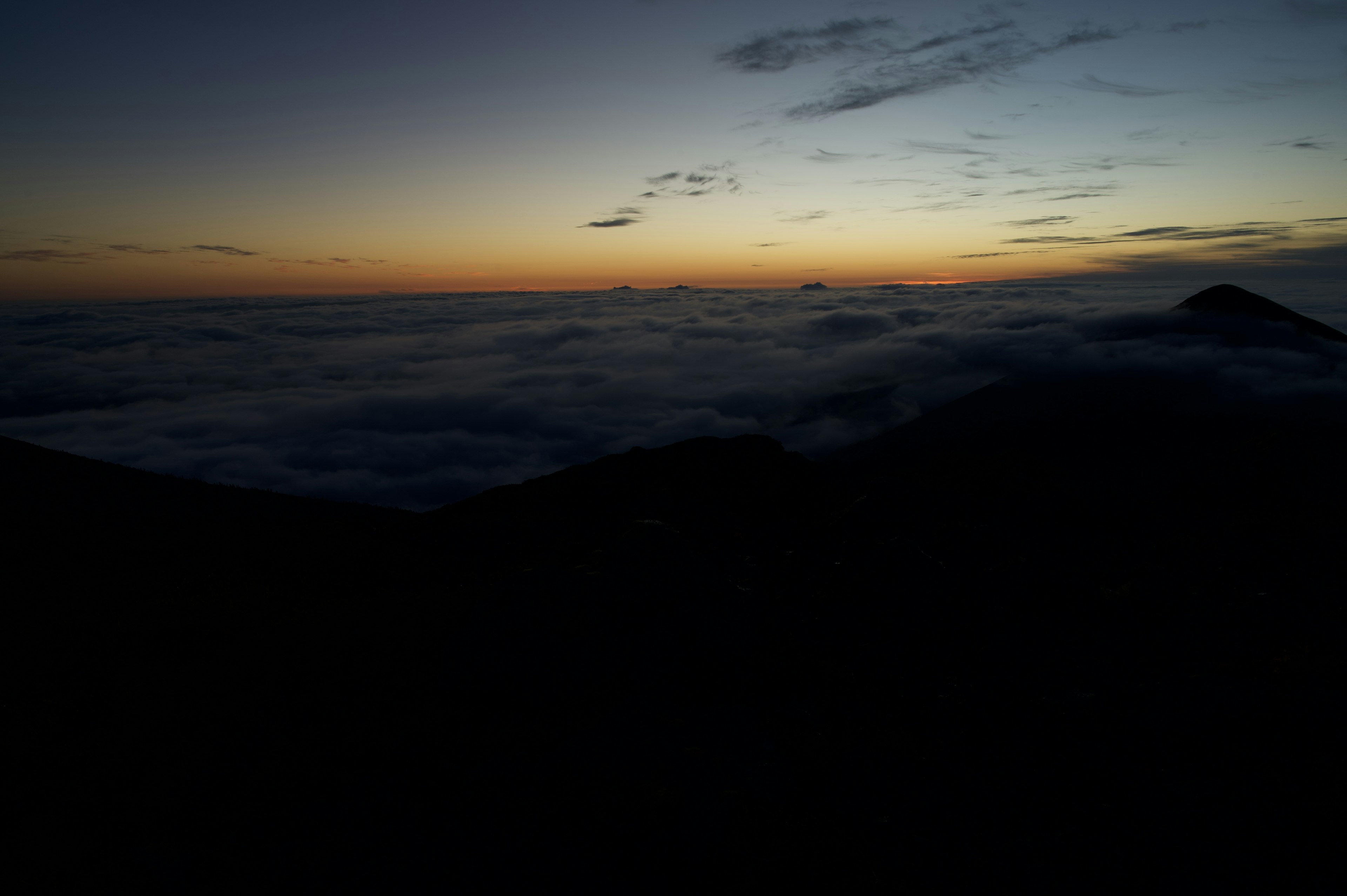 Silhouette di montagne con tramonto su un mare di nuvole