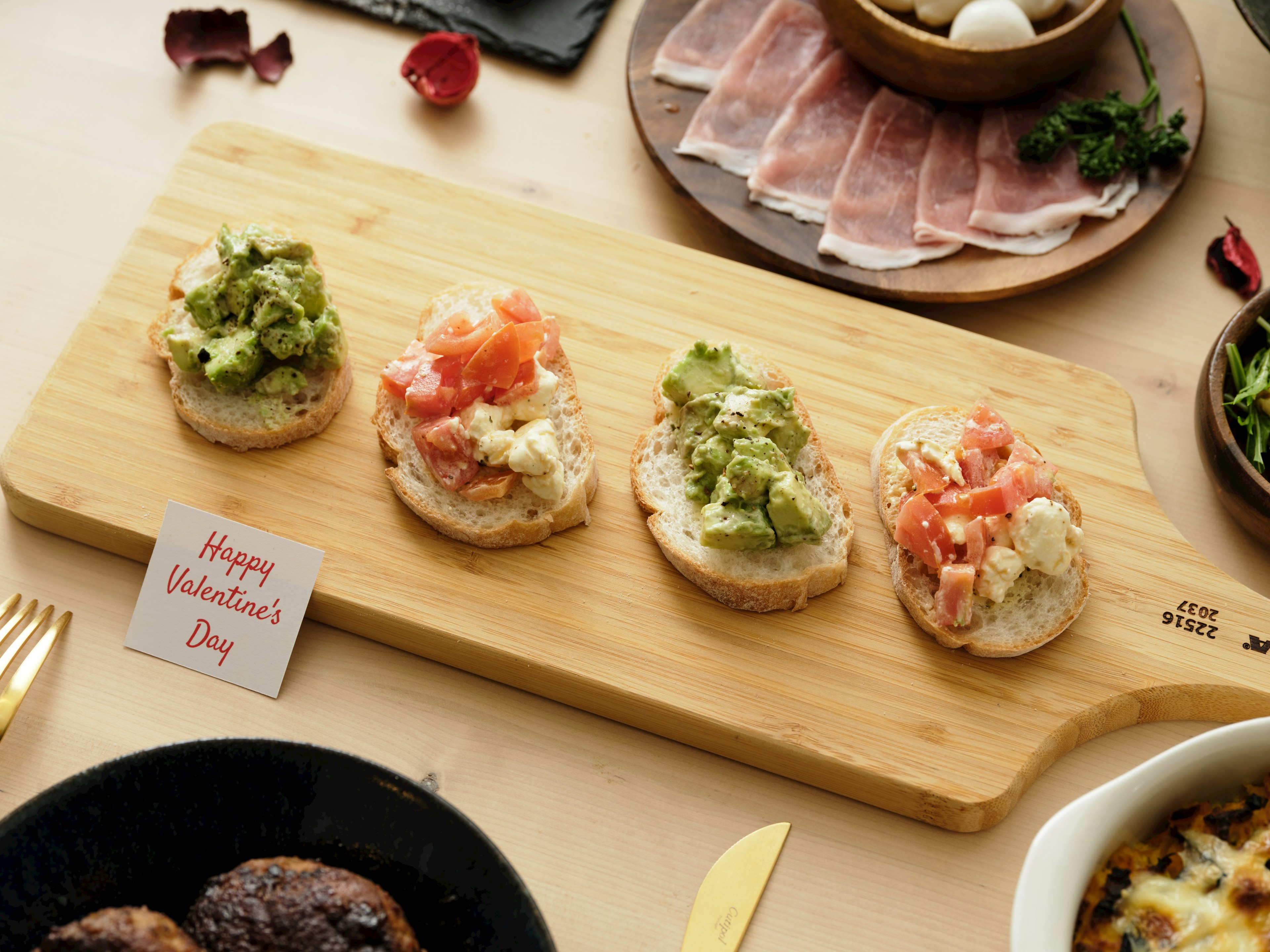 Cuatro tostadas dispuestas en una tabla de madera cada una cubierta con diferentes ingredientes una pequeña tarjeta dice Feliz Halloween