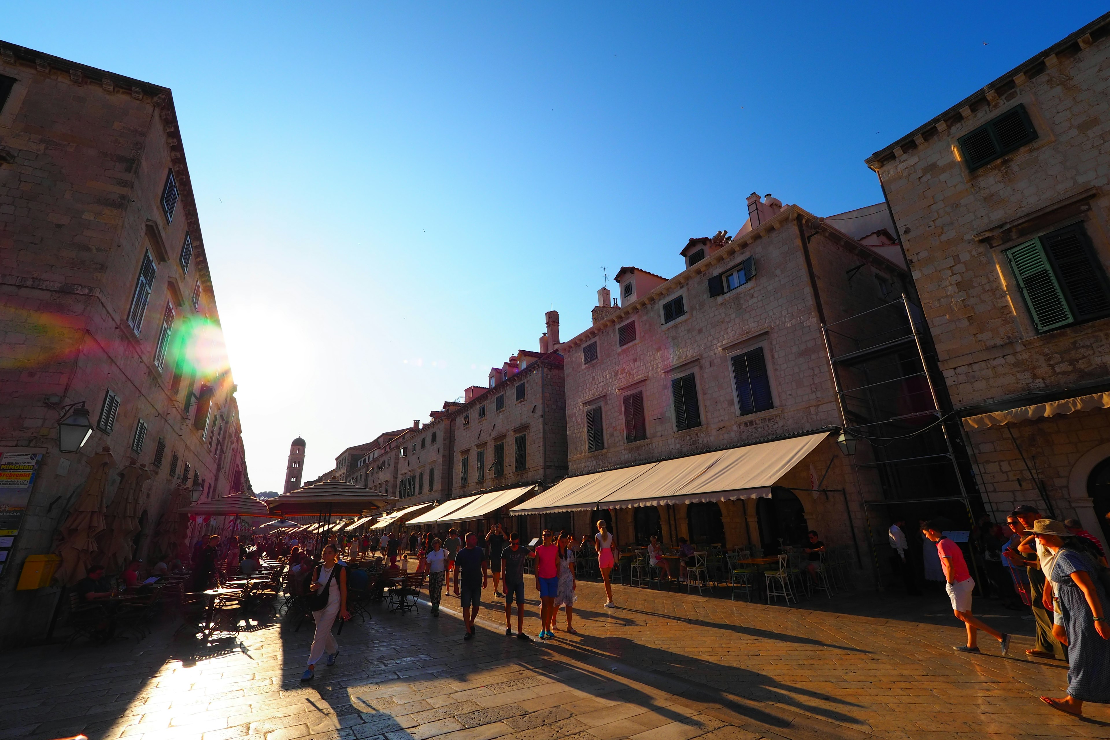 Tourists walking in an old street under a blue sky