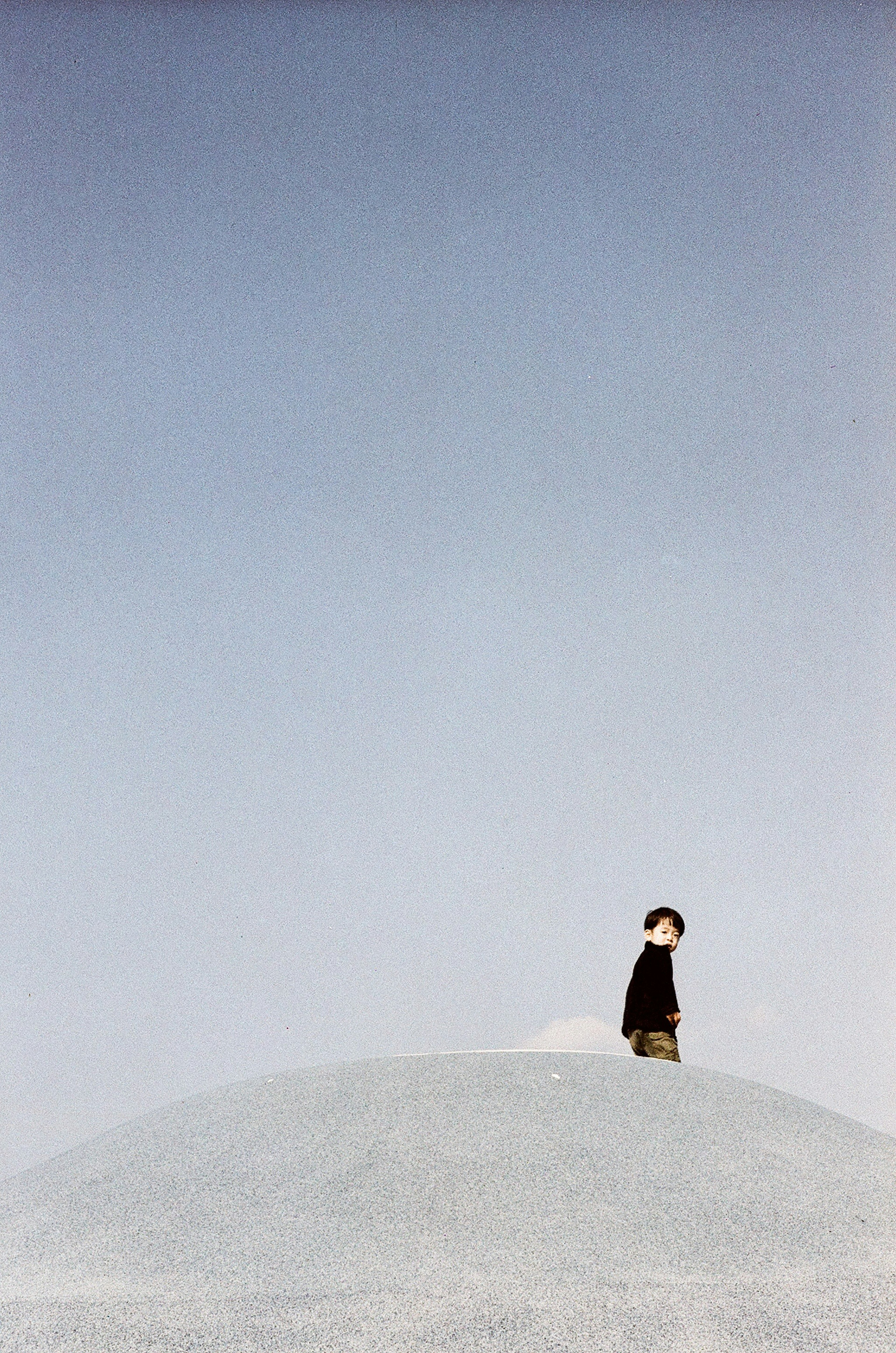 A person standing on a white hill under a blue sky