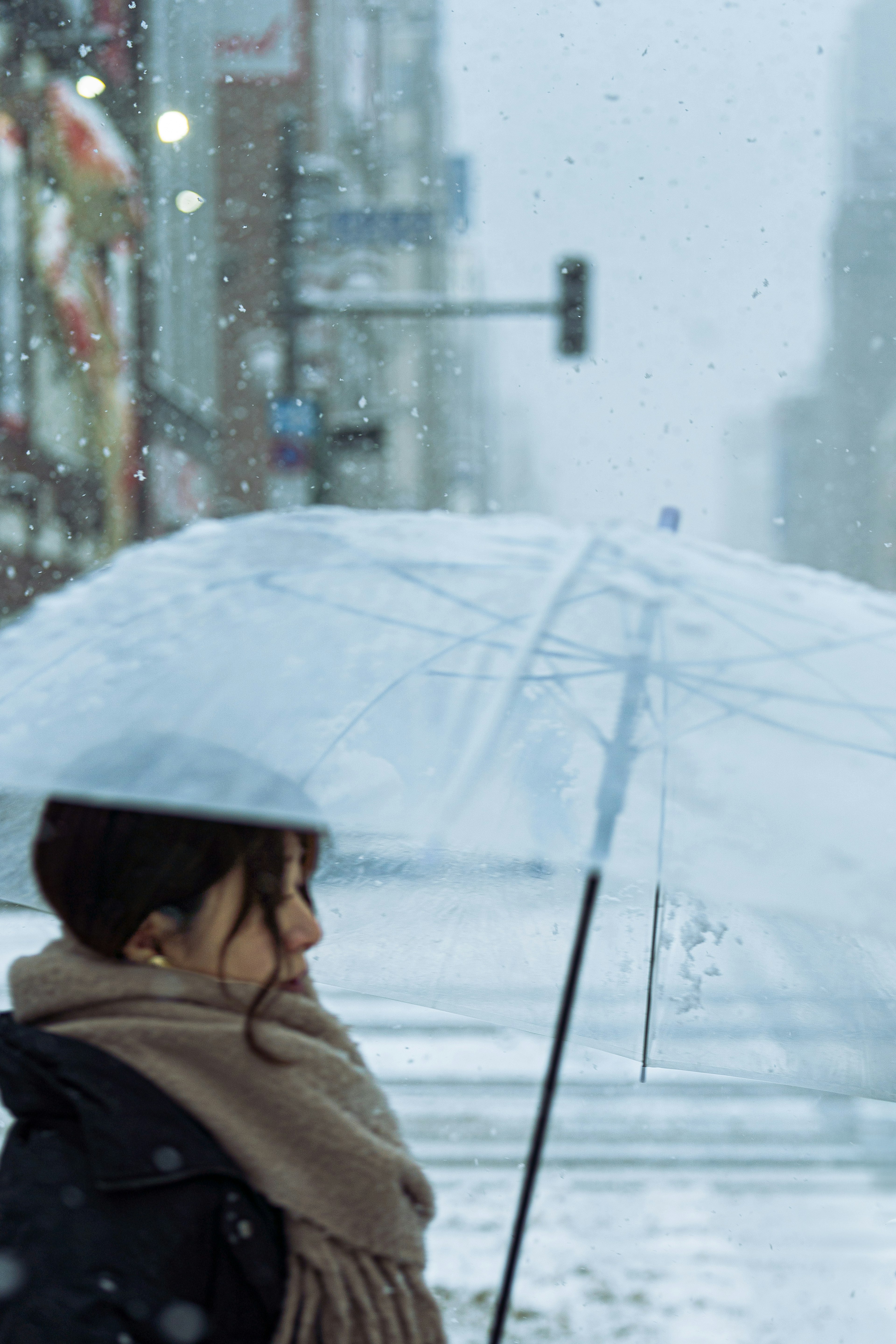 在雪中城市場景中撐傘的女人