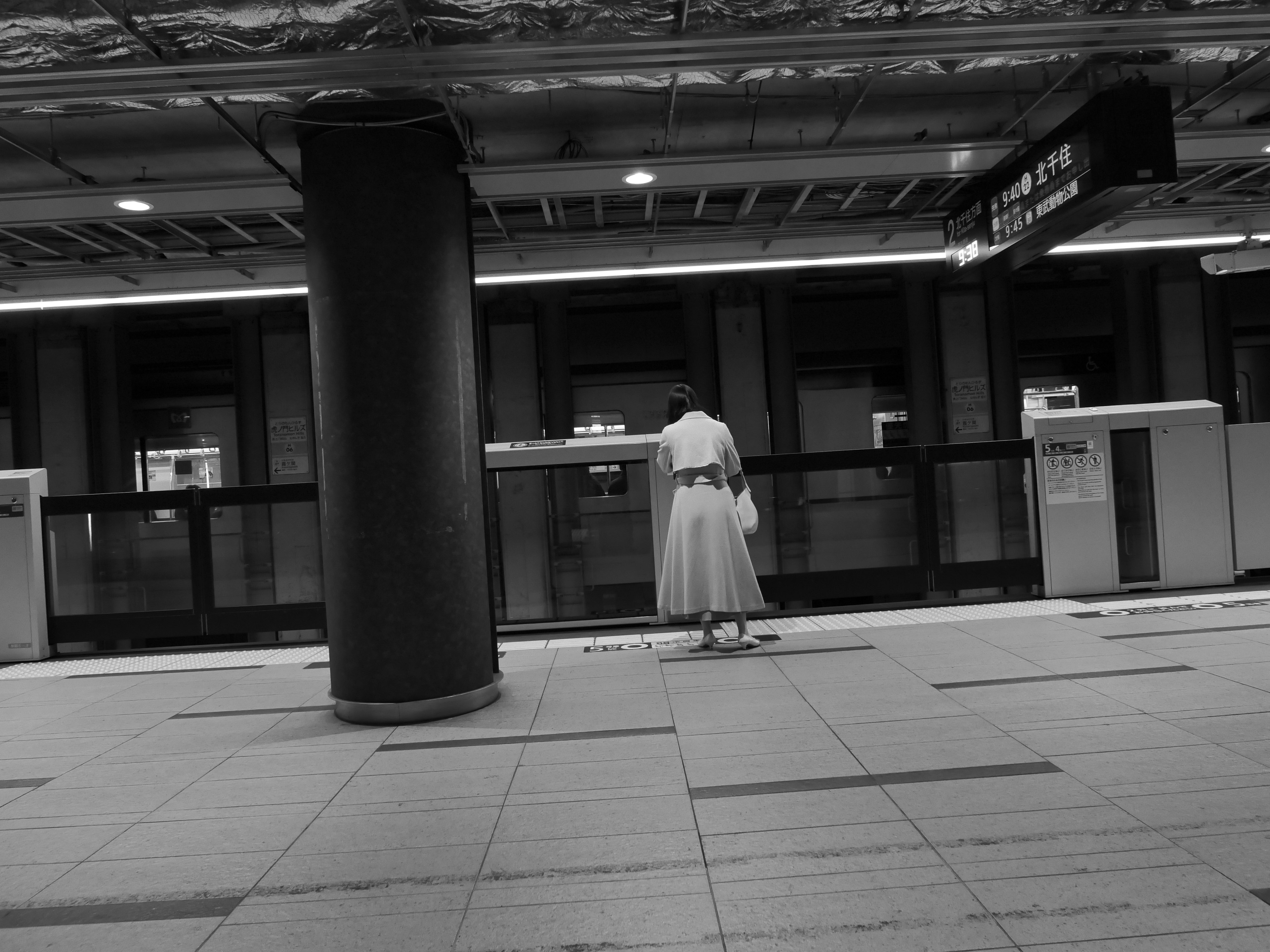 A woman standing in a monochrome subway station