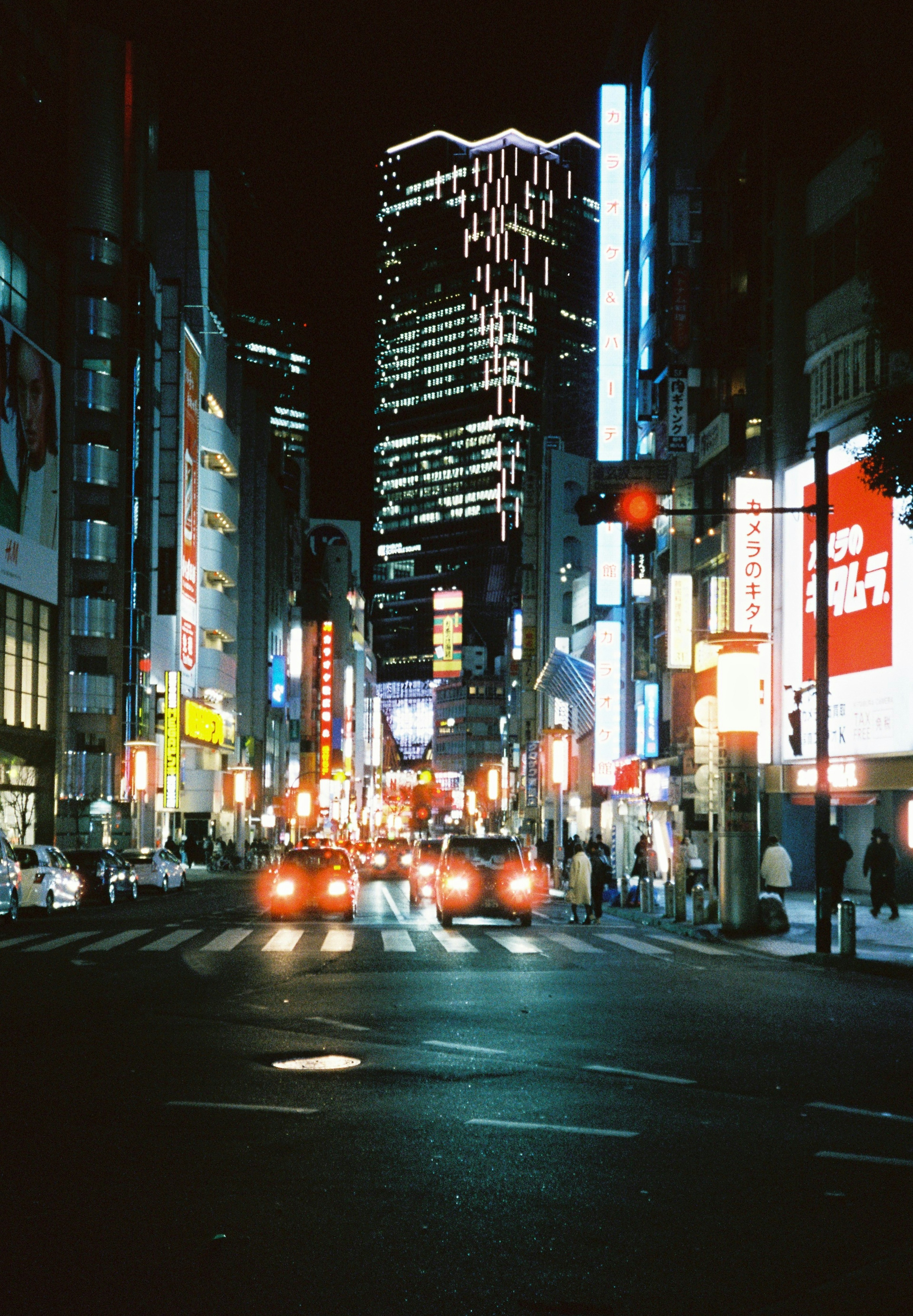 Paisaje urbano nocturno con luces de coches y letreros de neón