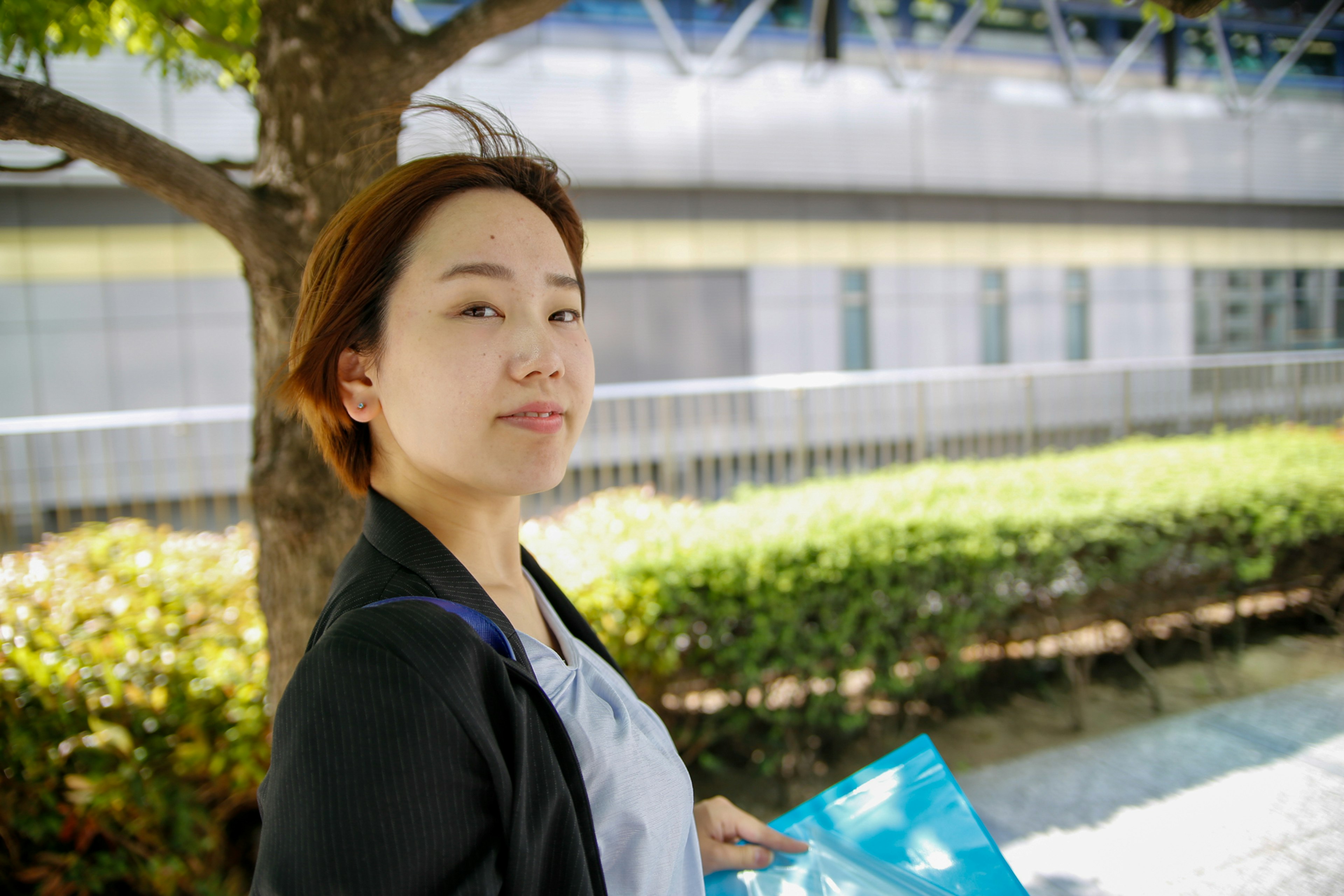 A woman holding blue documents in a park