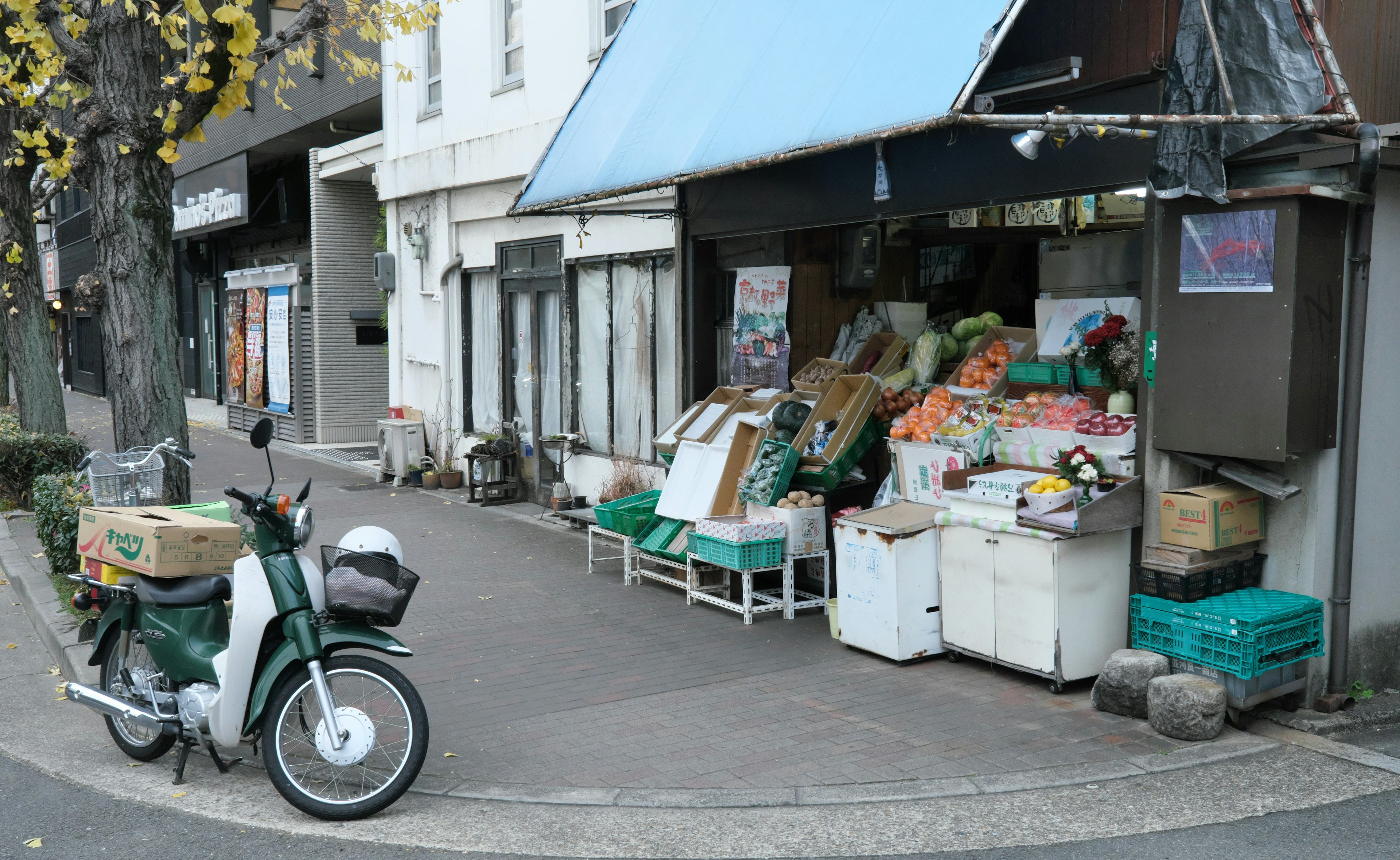 一個小角落商店，藍色遮陽棚下展示新鮮的蔬菜和水果