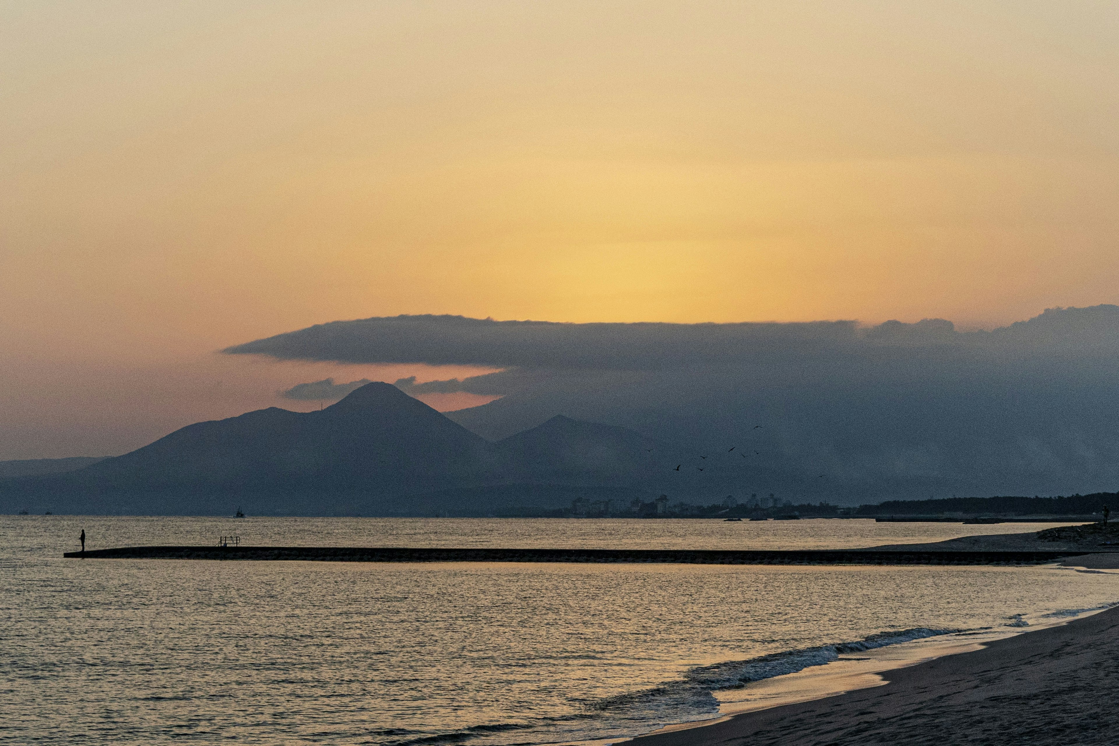 Paisaje costero al atardecer con montañas y nubes