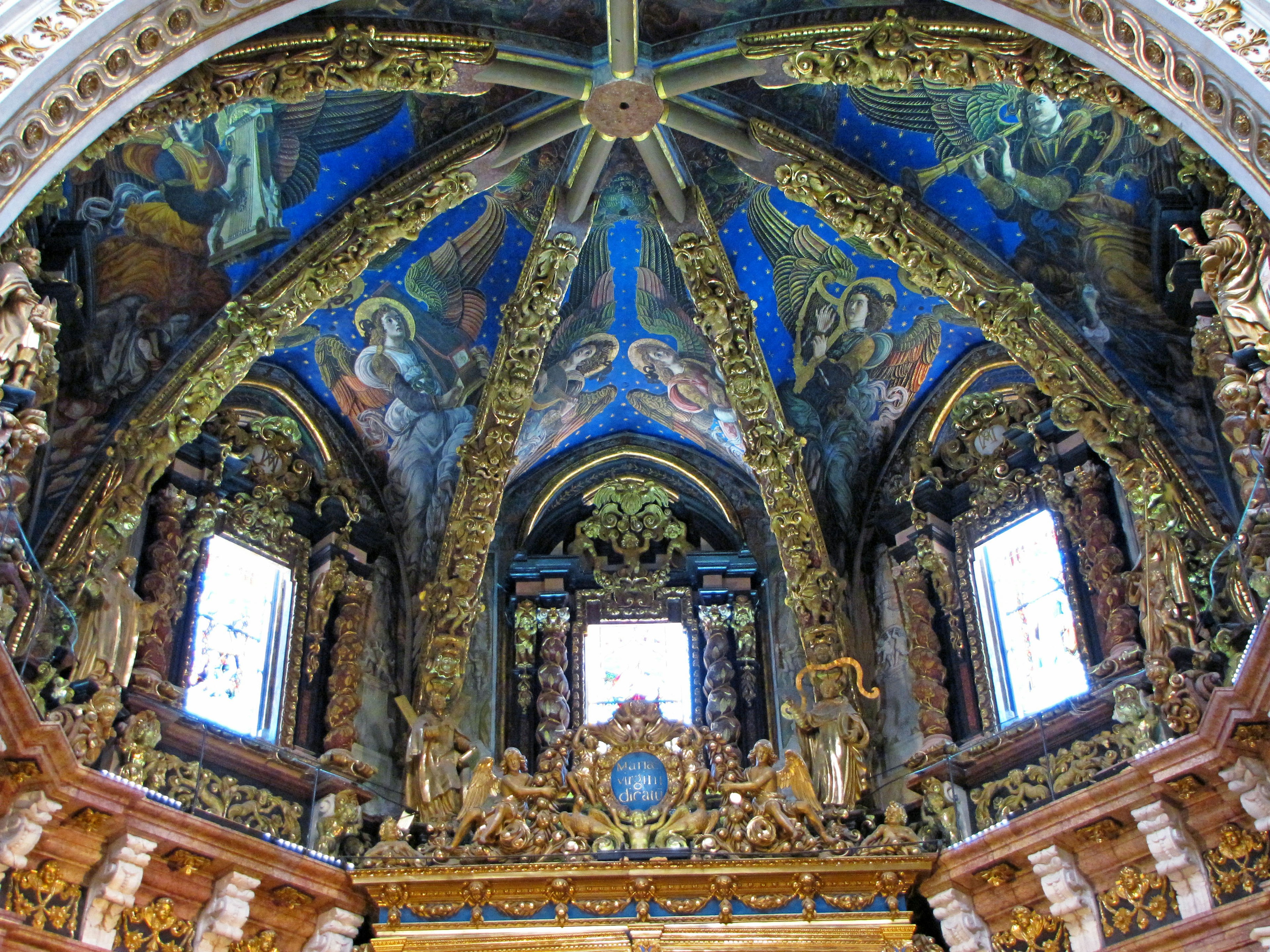 Interior of a beautifully decorated dome ceiling featuring colorful paintings and intricate golden sculptures