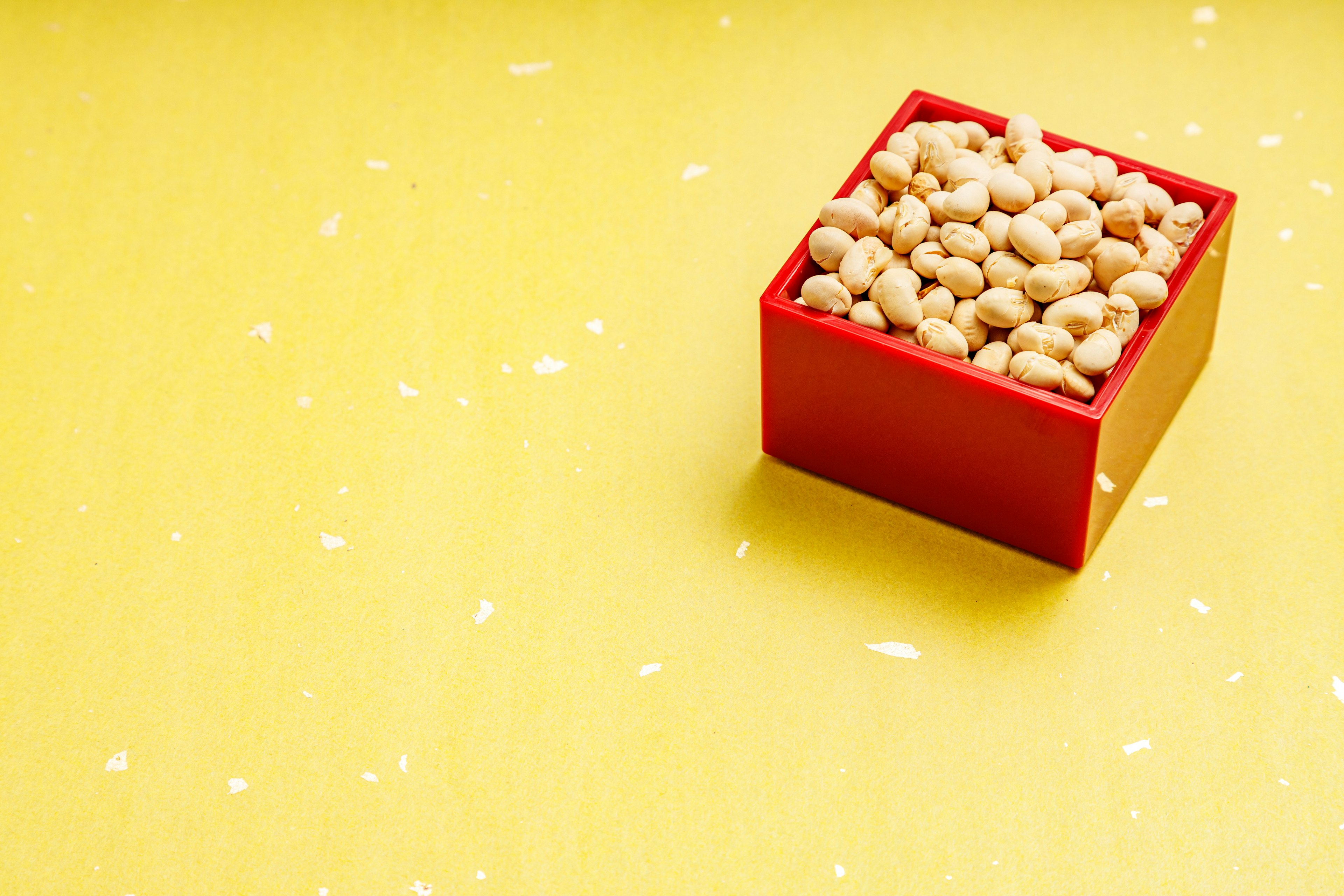 Una caja roja llena de frijoles blancos sobre un fondo amarillo