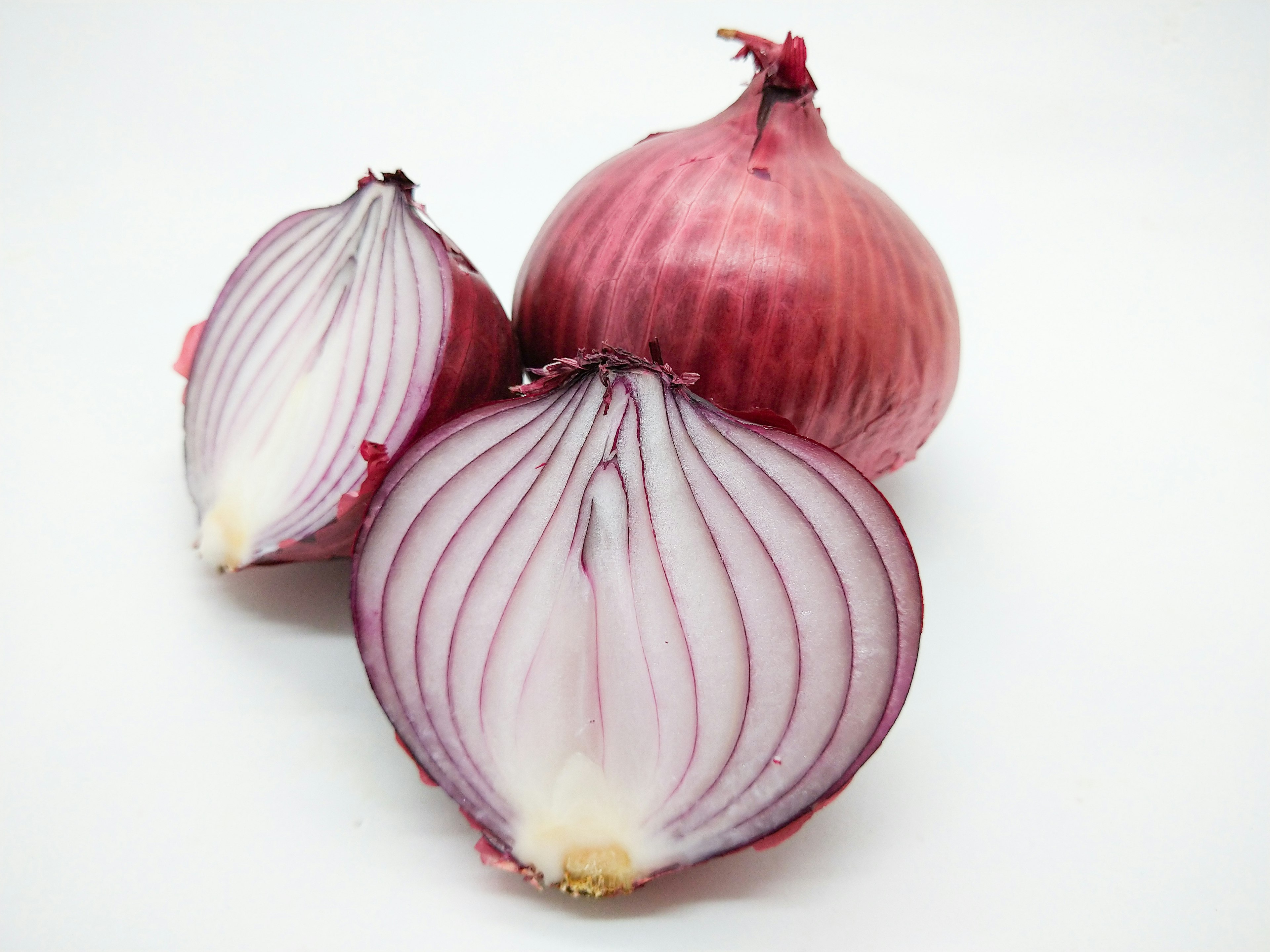 Three red onions including one cut in half revealing layered interior