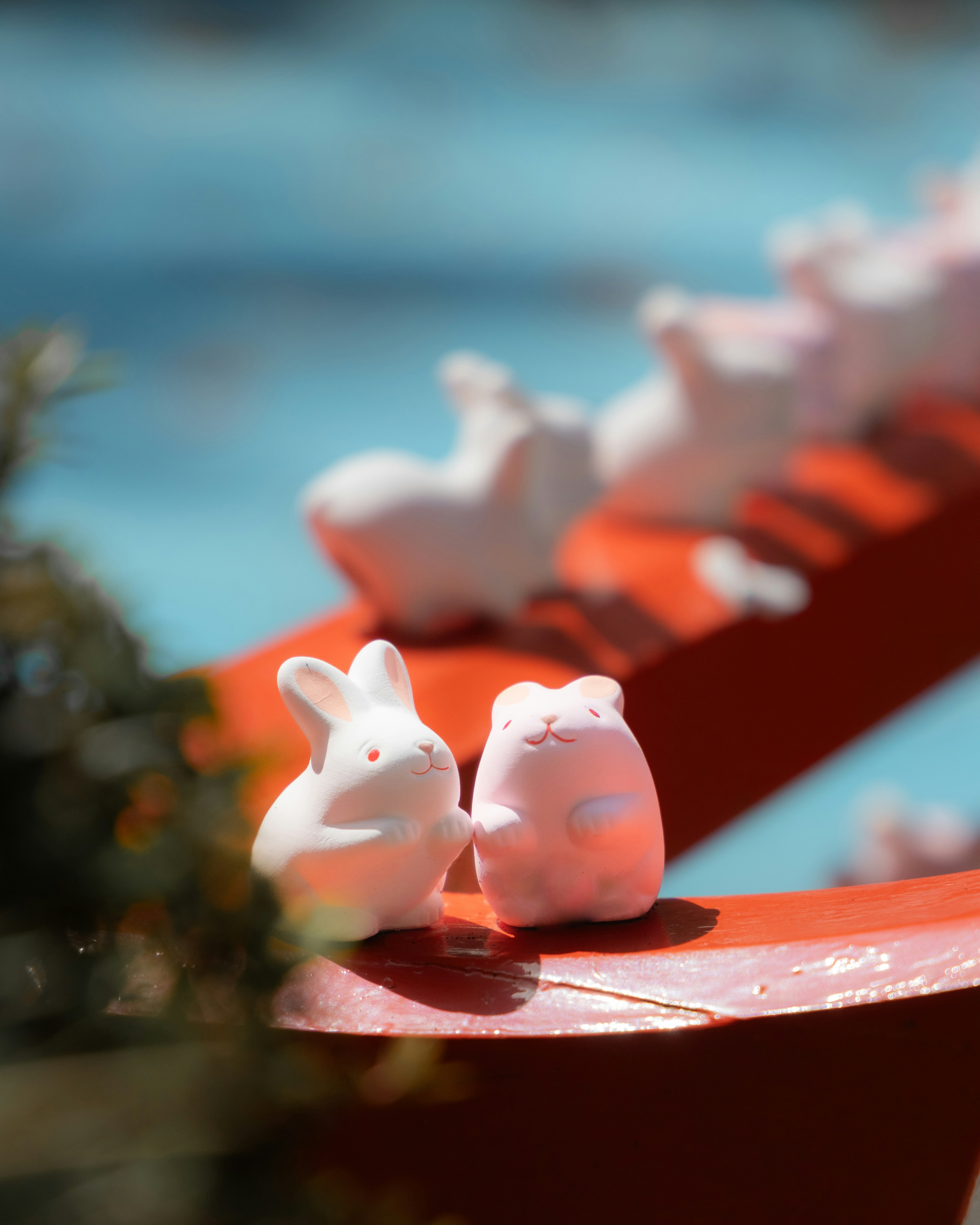 White rabbit and bear figurines on a red platform with a blurred background