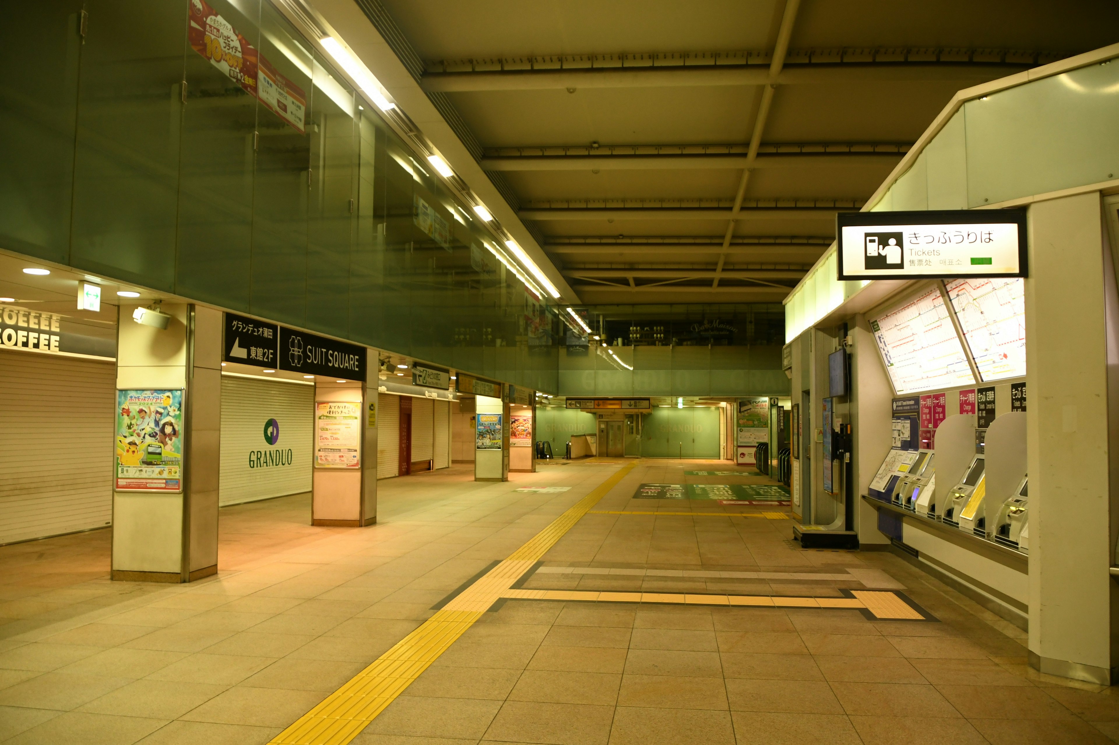 Piattaforma della stazione vuota con illuminazione a soffitto e biglietterie automatiche