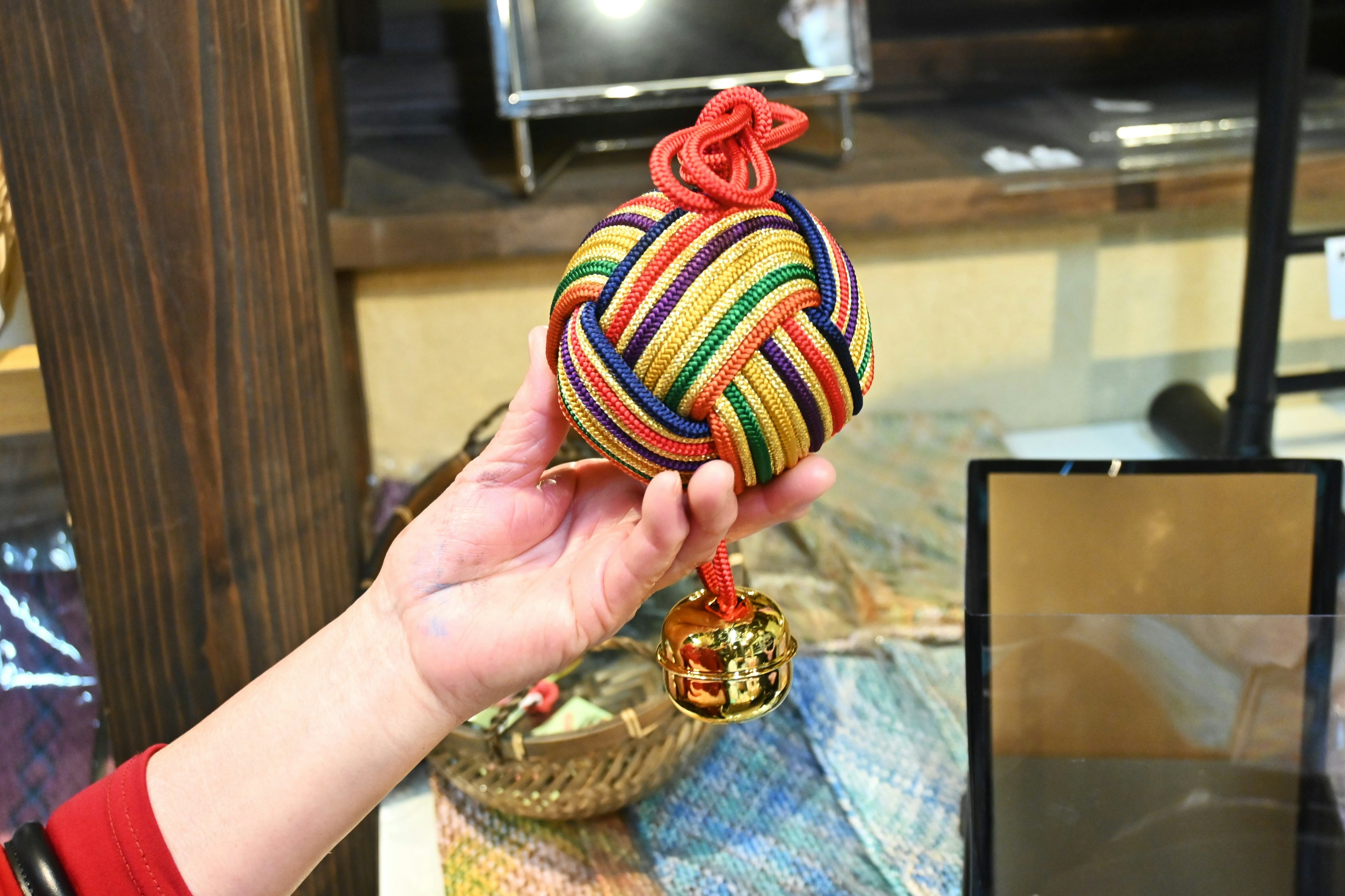 Colorful traditional ball held in hand with red knot detail