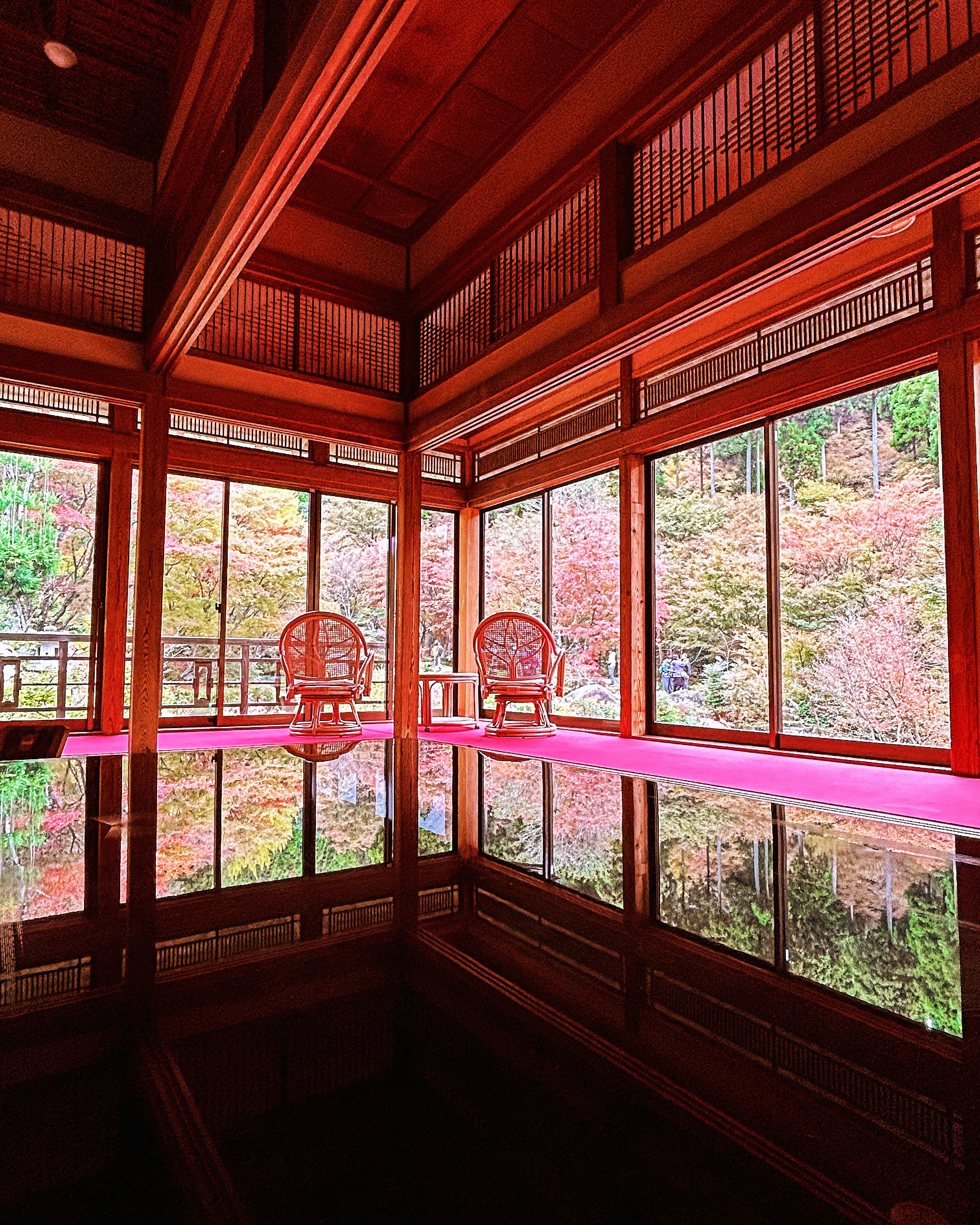 Chambre japonaise traditionnelle avec vue sur le feuillage d'automne et sol réfléchissant avec deux chaises