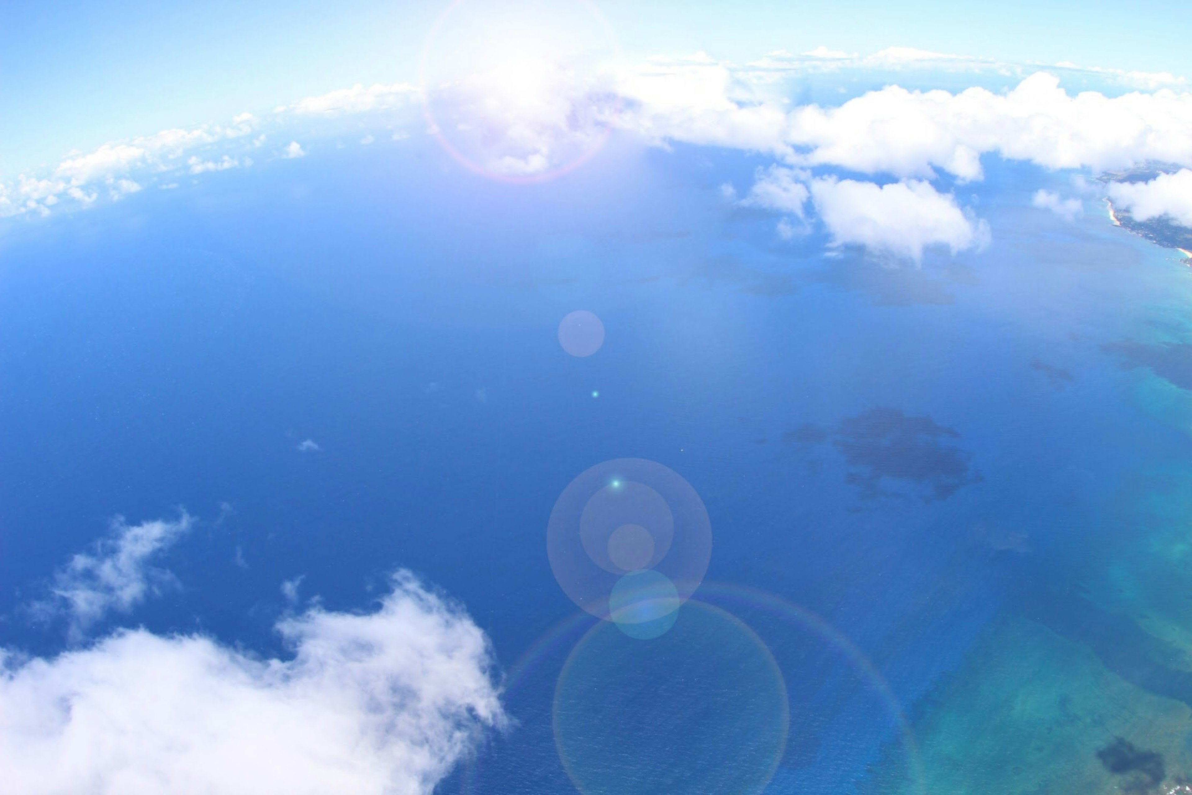 Aerial view of a blue ocean and white clouds under a bright sky