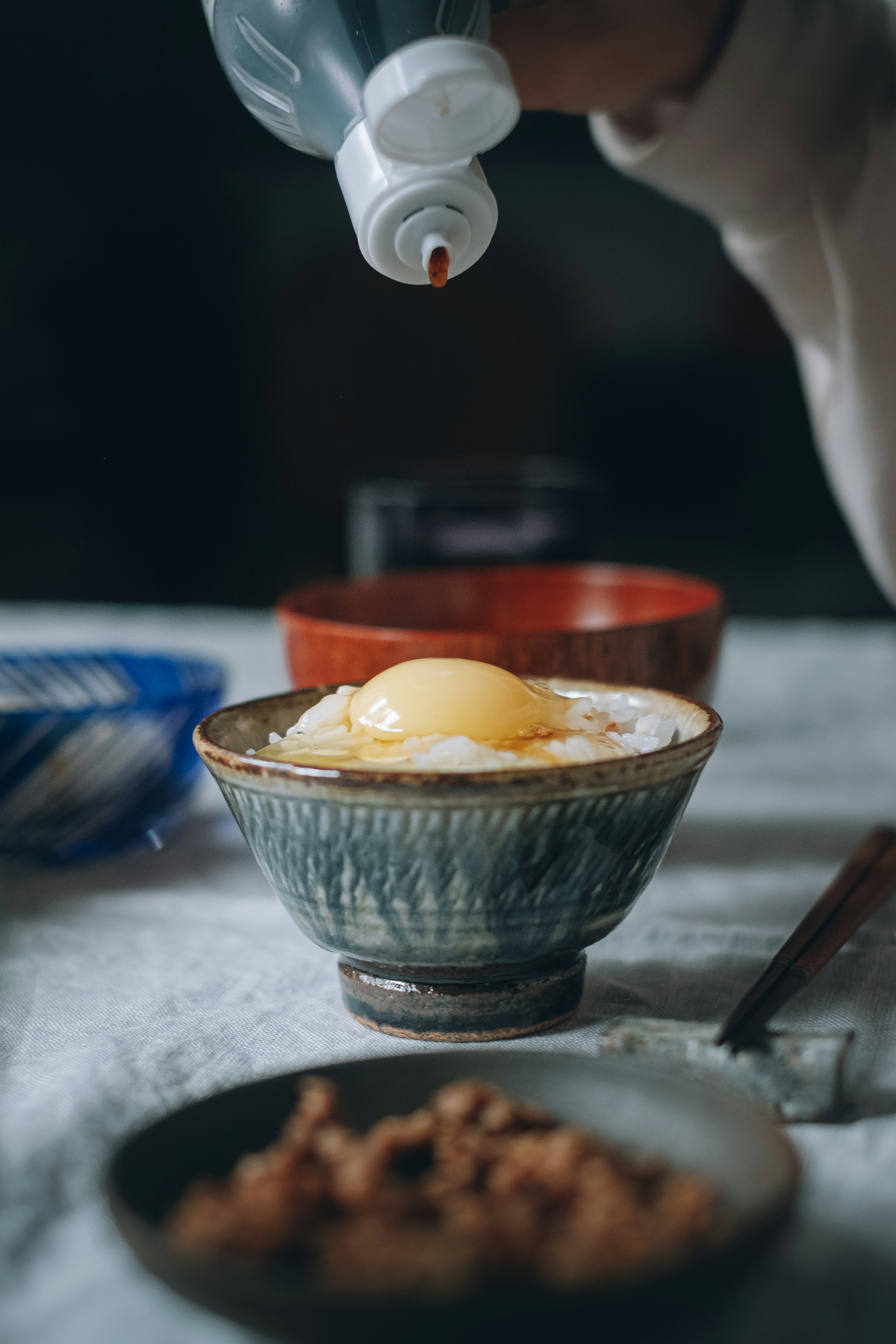 Semangkuk nasi dengan telur mentah yang disiram saus