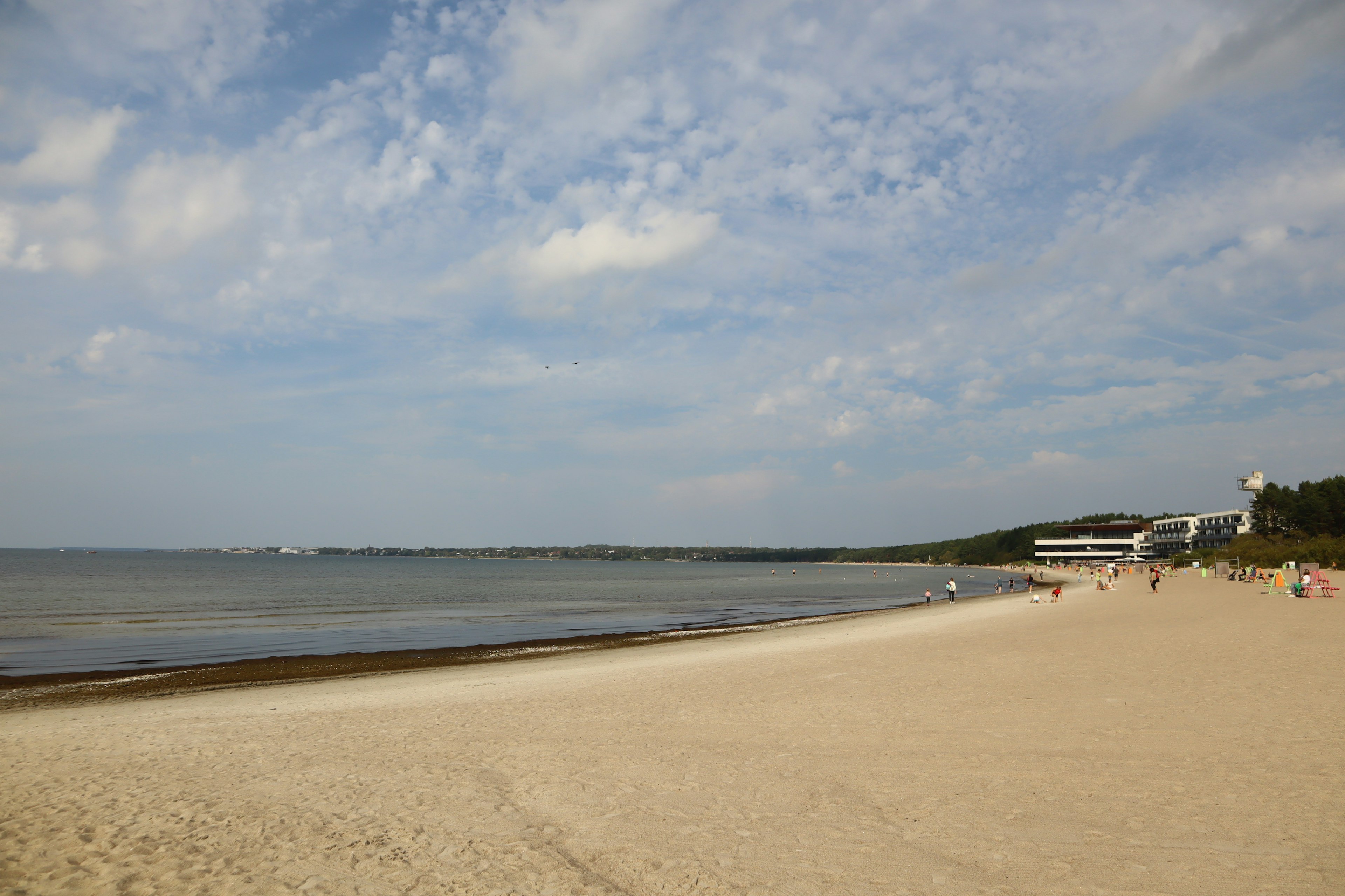 ชายหาดที่มีทรายขาวและทะเลสีน้ำเงินใต้ท้องฟ้าที่มีเมฆ