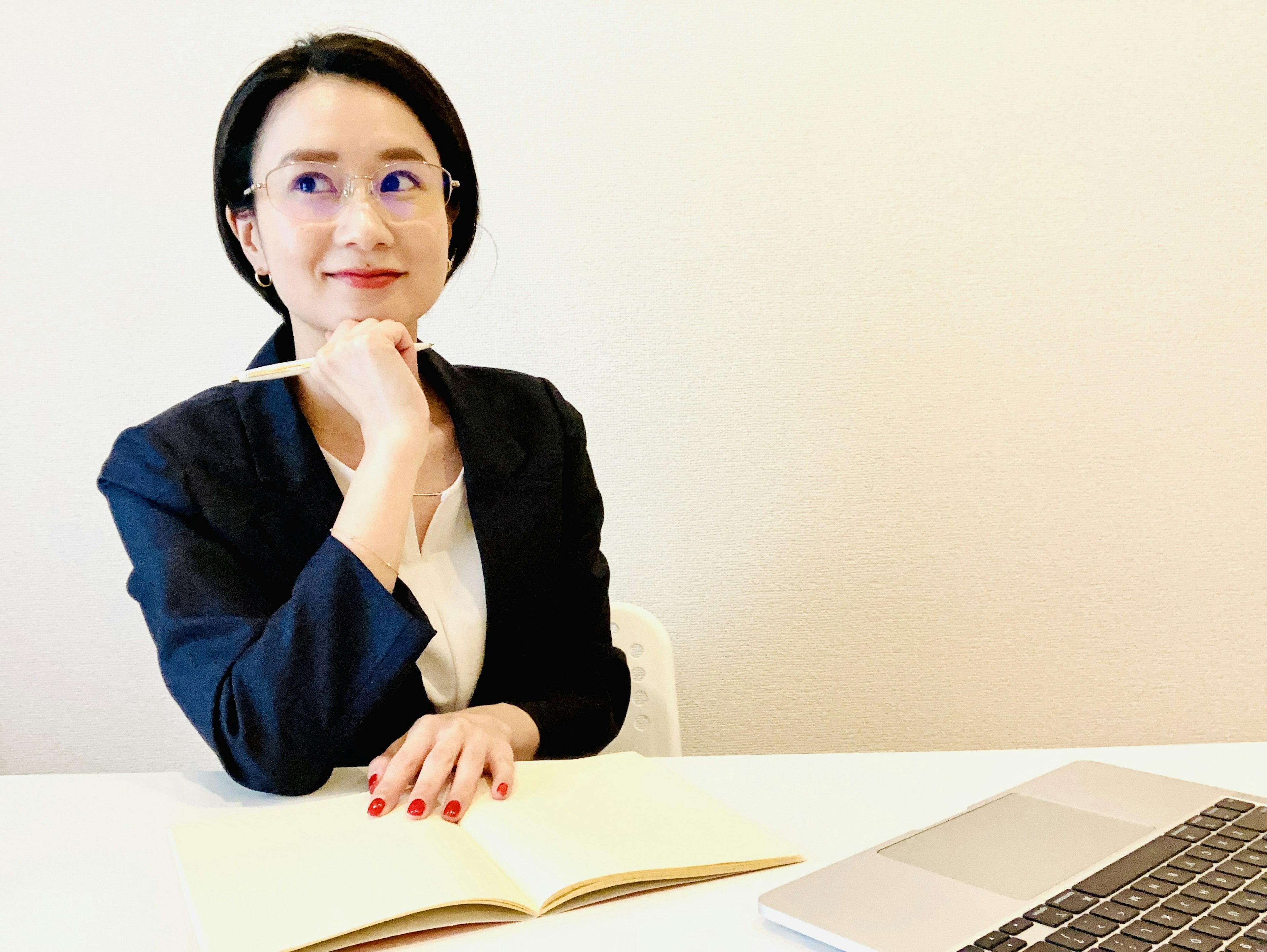 Woman in a business suit thinking thoughtfully in front of a laptop