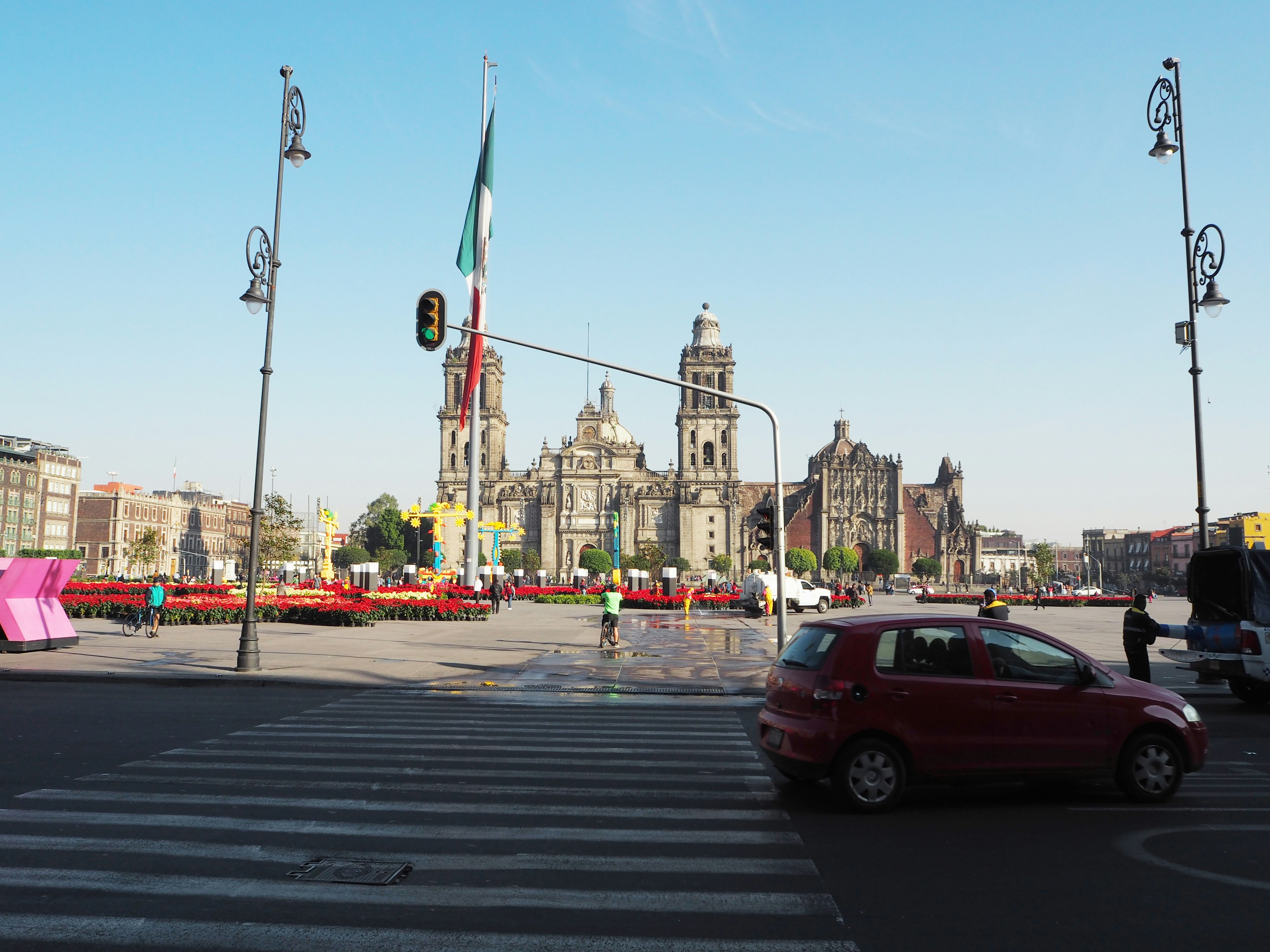 View of a square in Mexico City featuring a red car and historic buildings