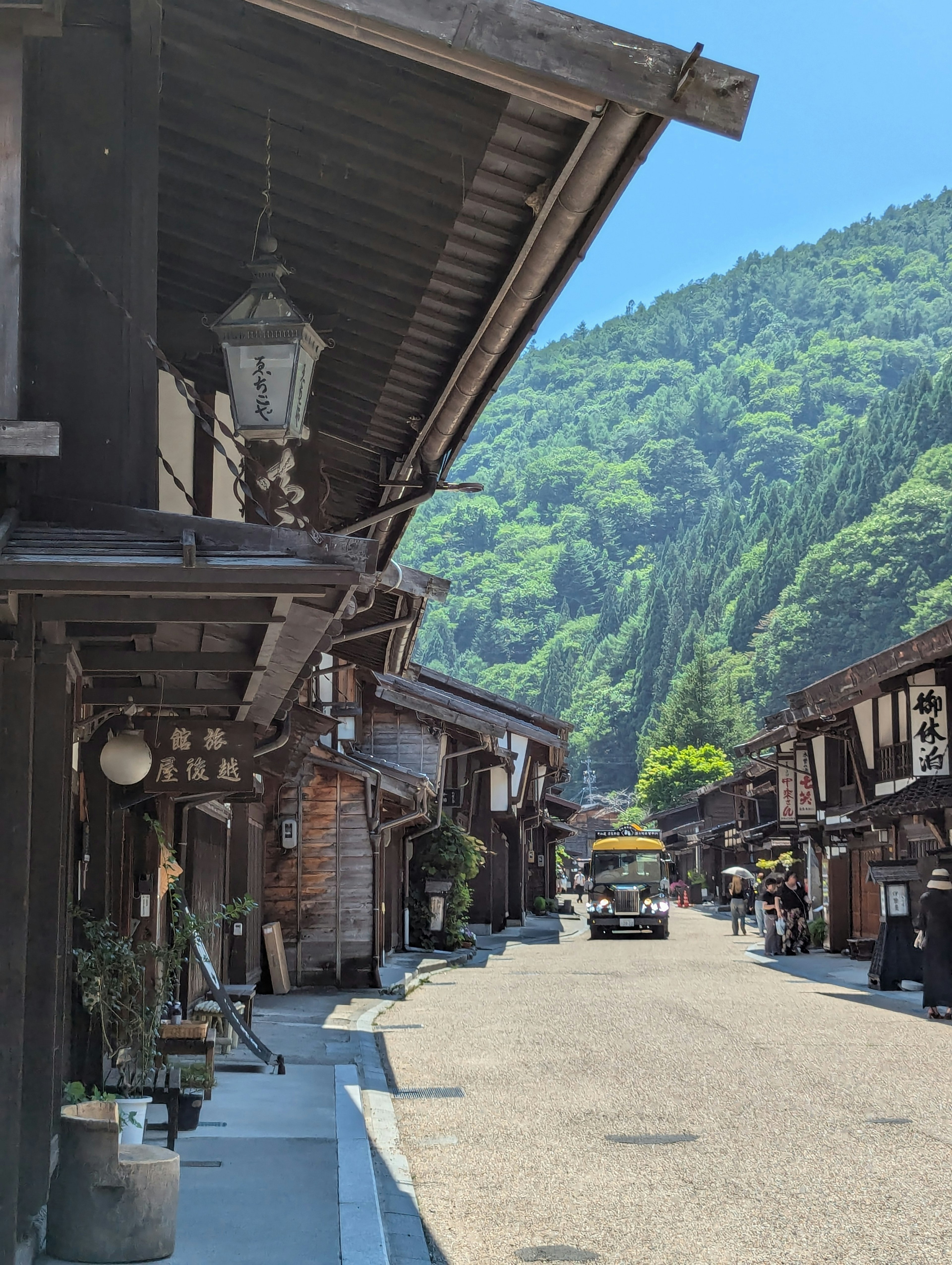 Ruhige Straße gesäumt von traditionellen Holzhäusern üppige grüne Berge im Hintergrund