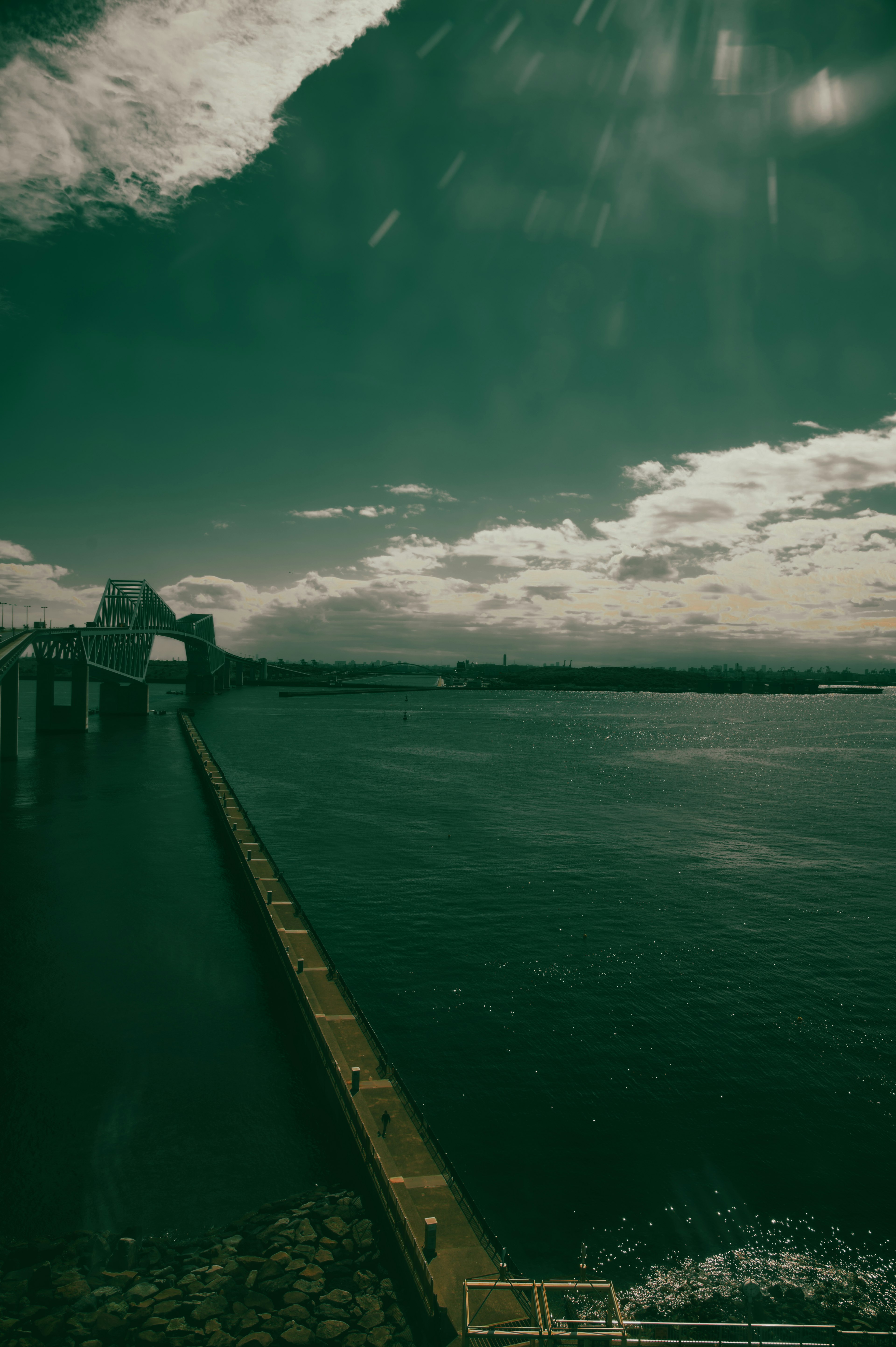 水面に映る雲と長い桟橋が見える風景