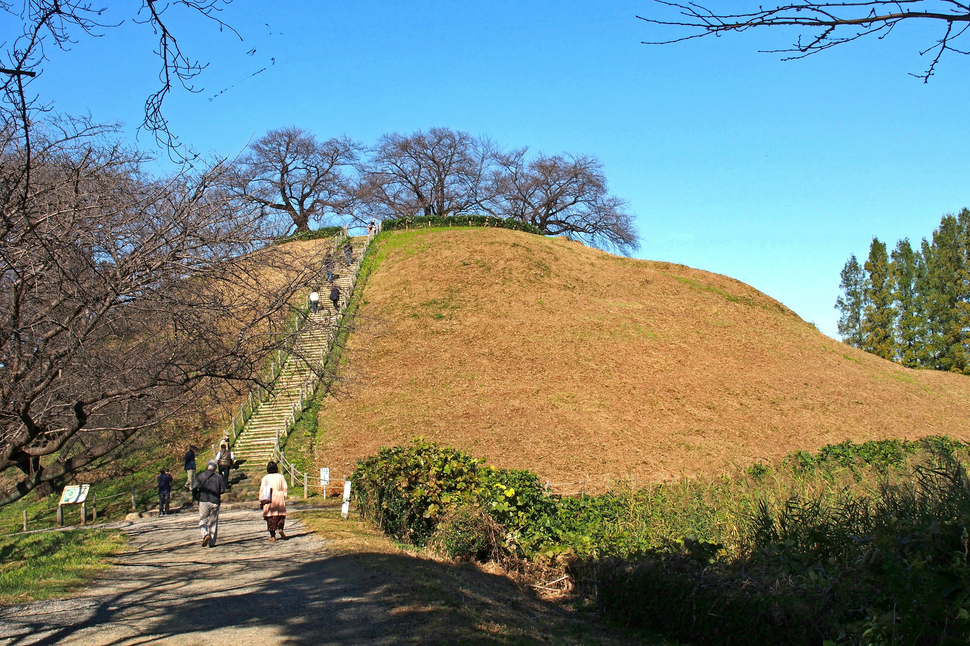 Túmulo verde con escaleras y visitantes