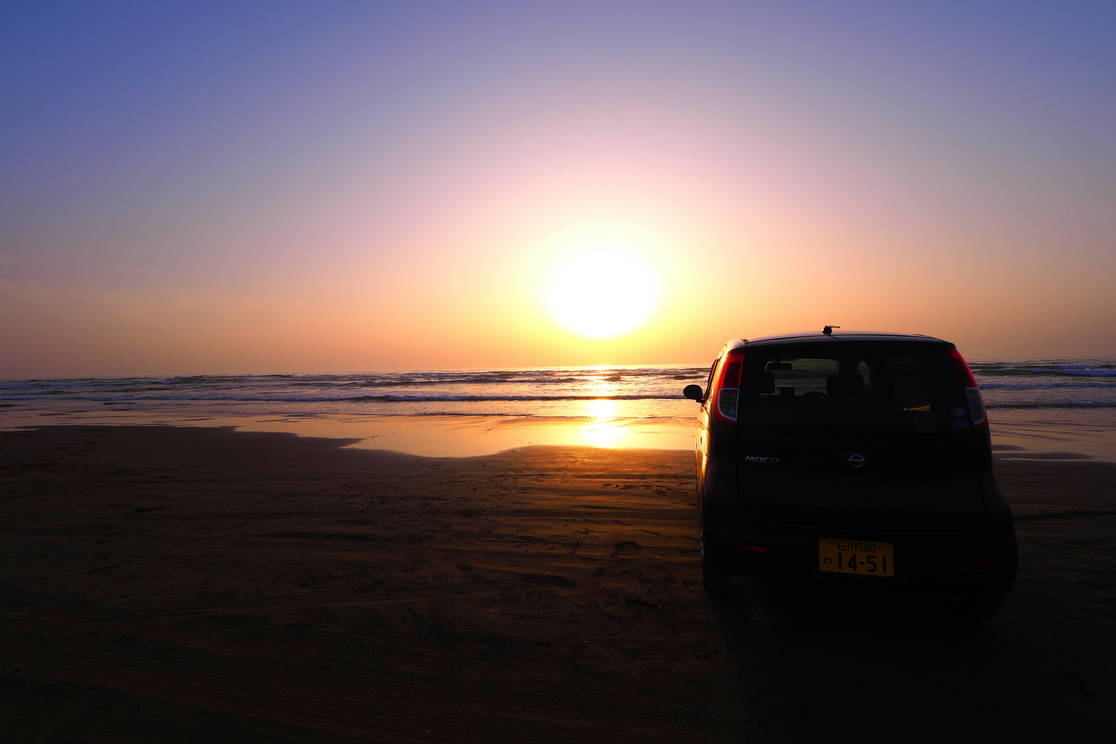 海岸での夕焼けを背景にした黒い車