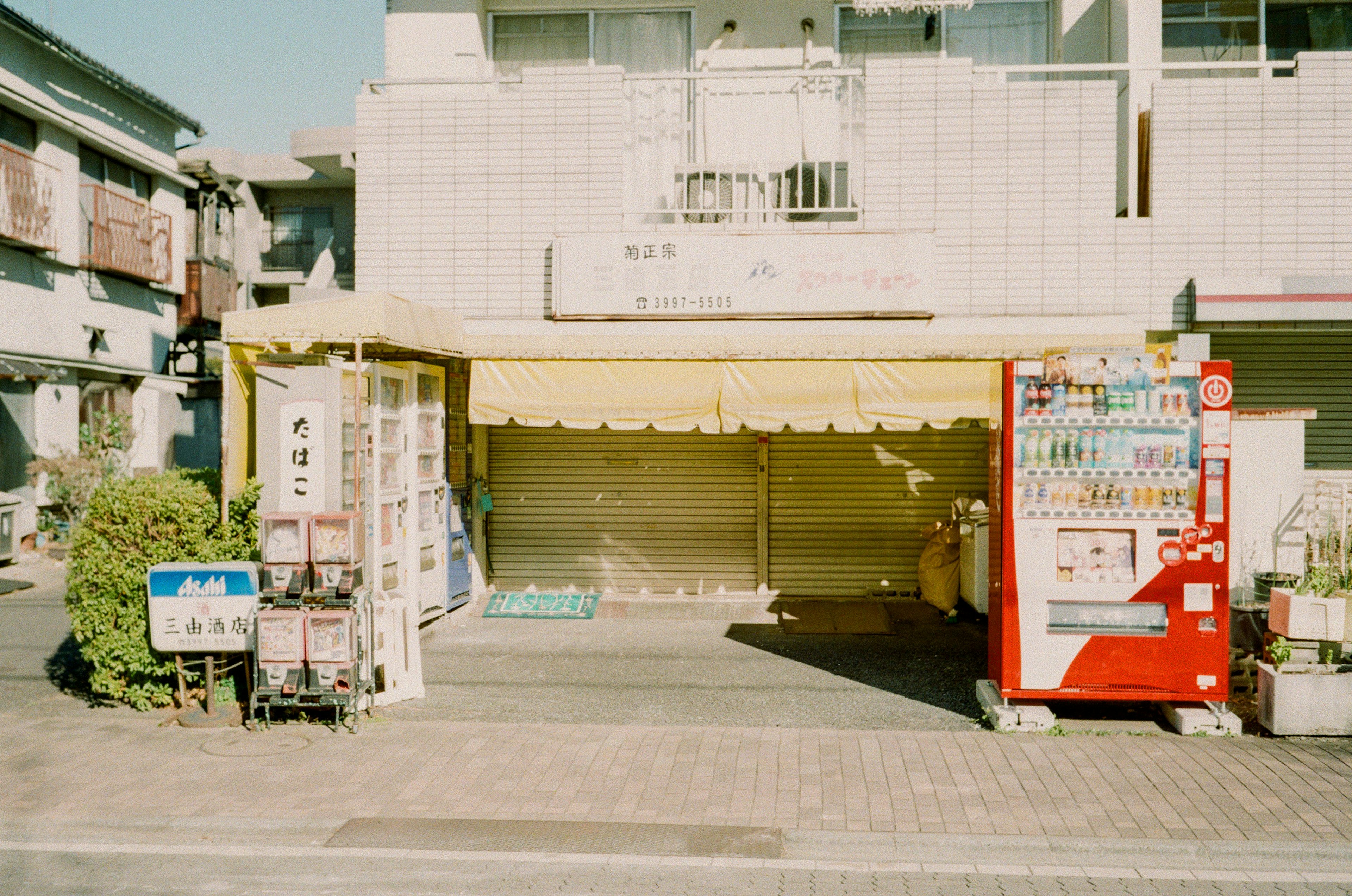 空店面前景有黄色遮阳篷和自动售货机