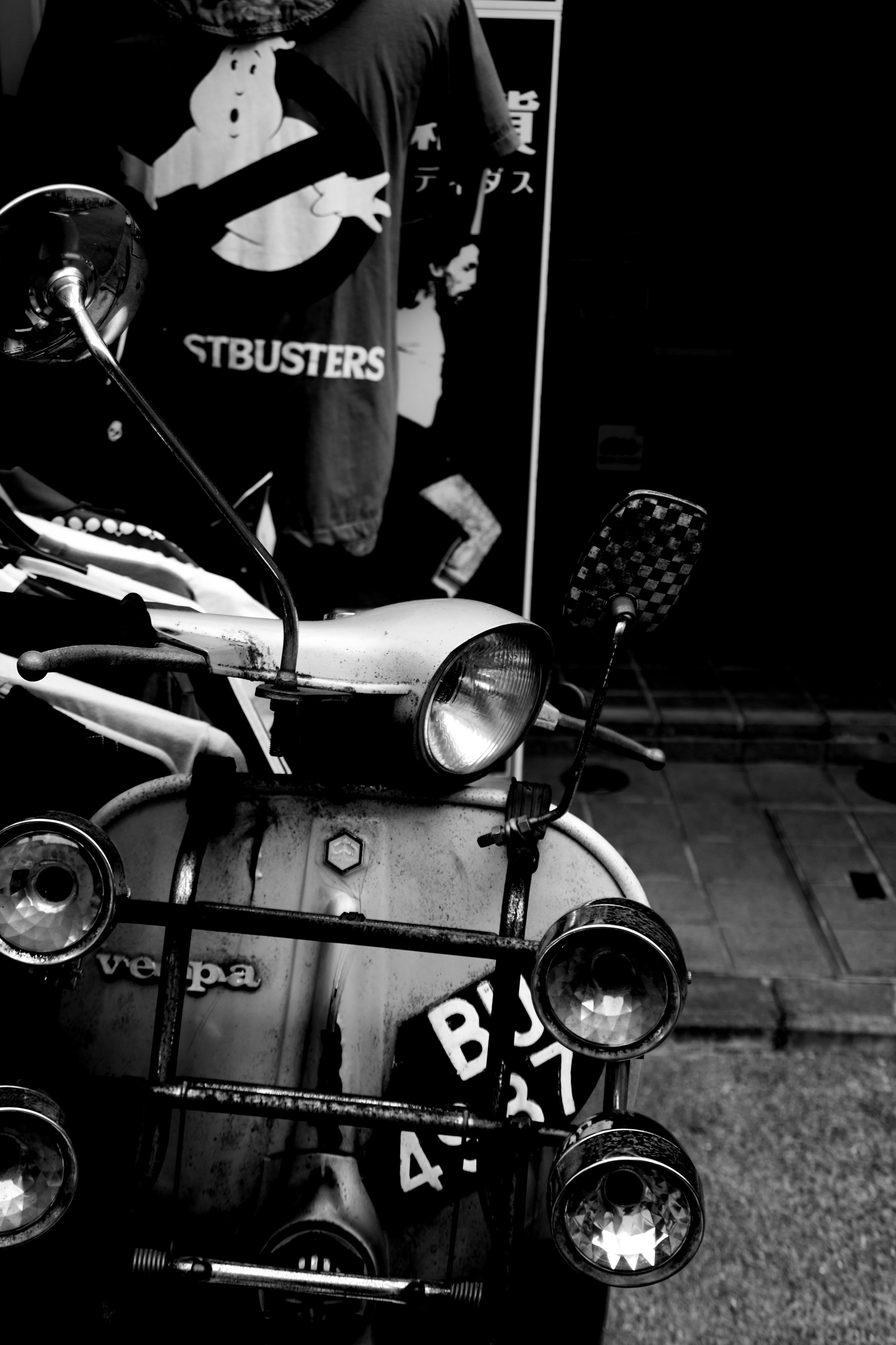 Immagine in bianco e nero con uno scooter vintage e una maglietta dei Ghostbusters