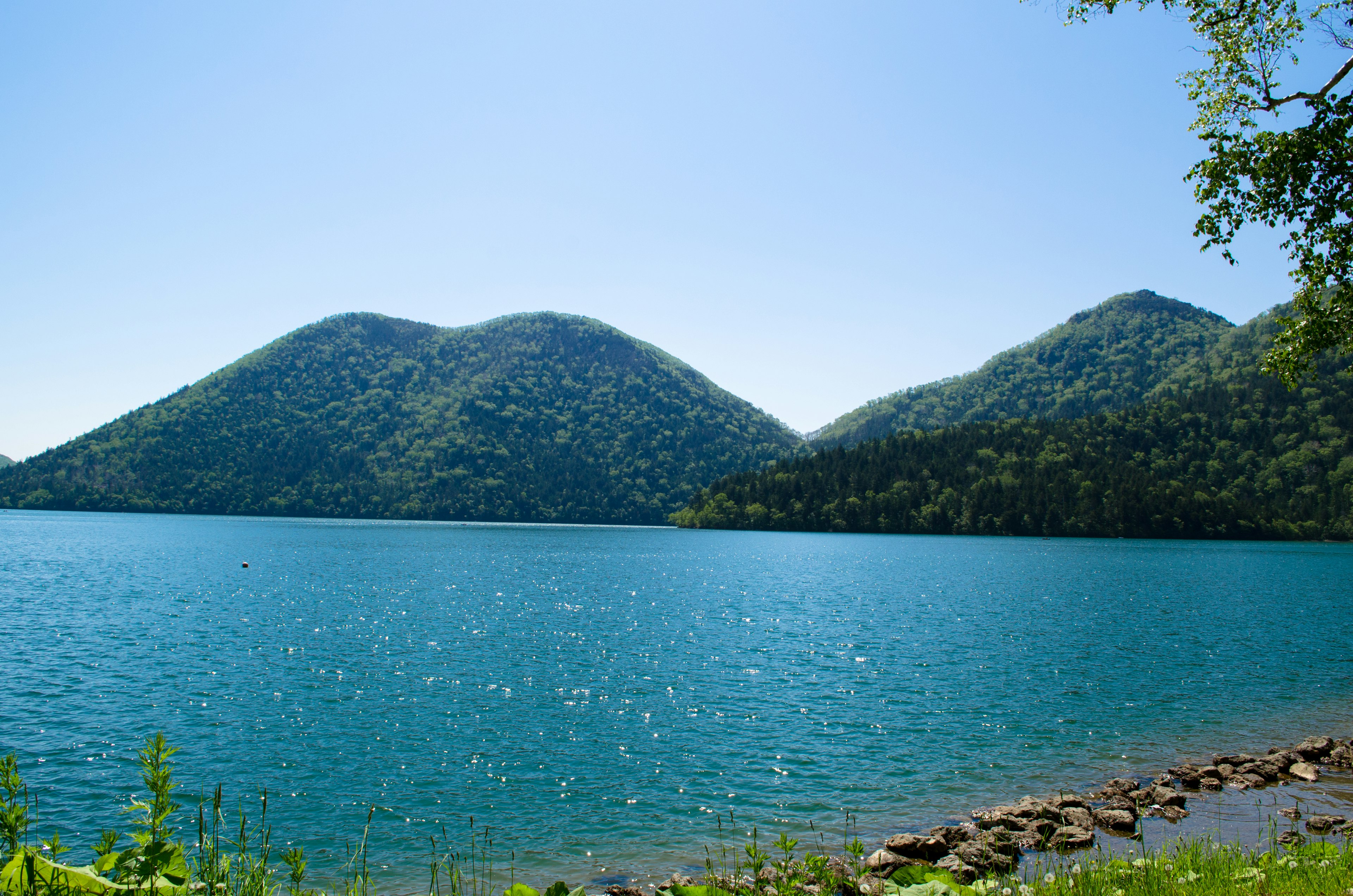 Vista escénica de un lago azul con colinas verdes al fondo