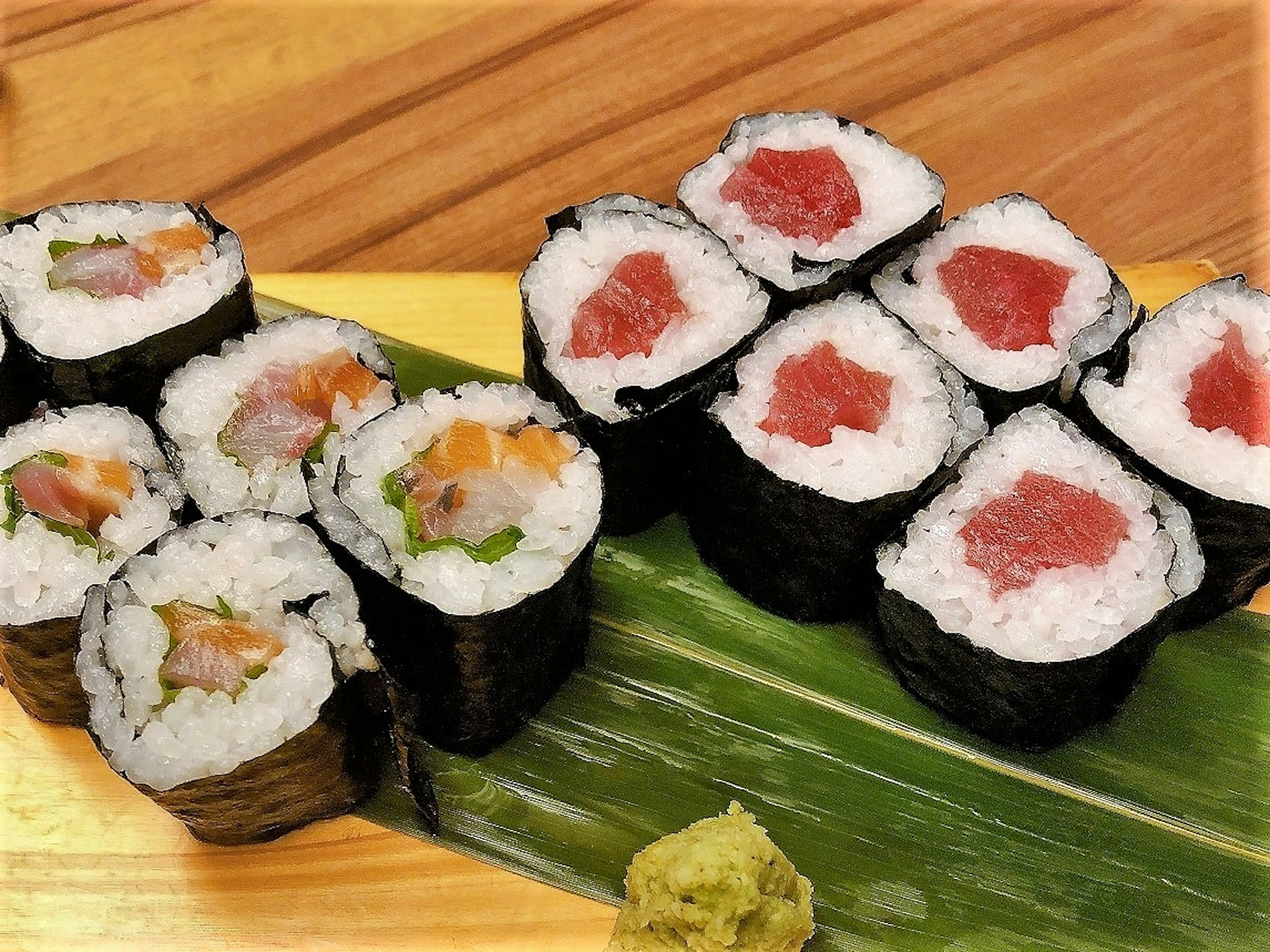 A plate of vibrant sushi rolls arranged on a green leaf