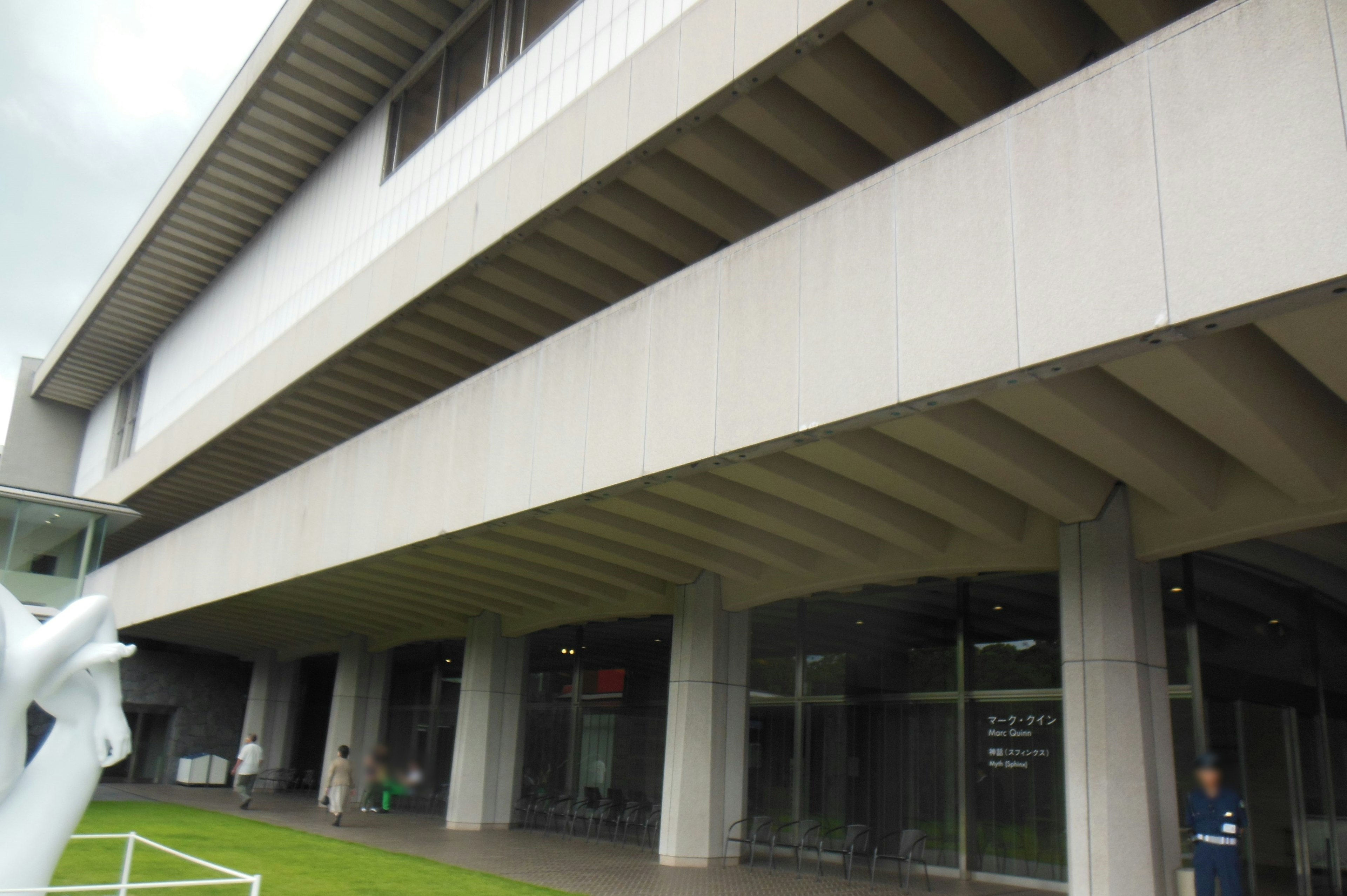 Extérieur d'un bâtiment moderne avec de grandes fenêtres et une structure en béton devant de l'herbe verte