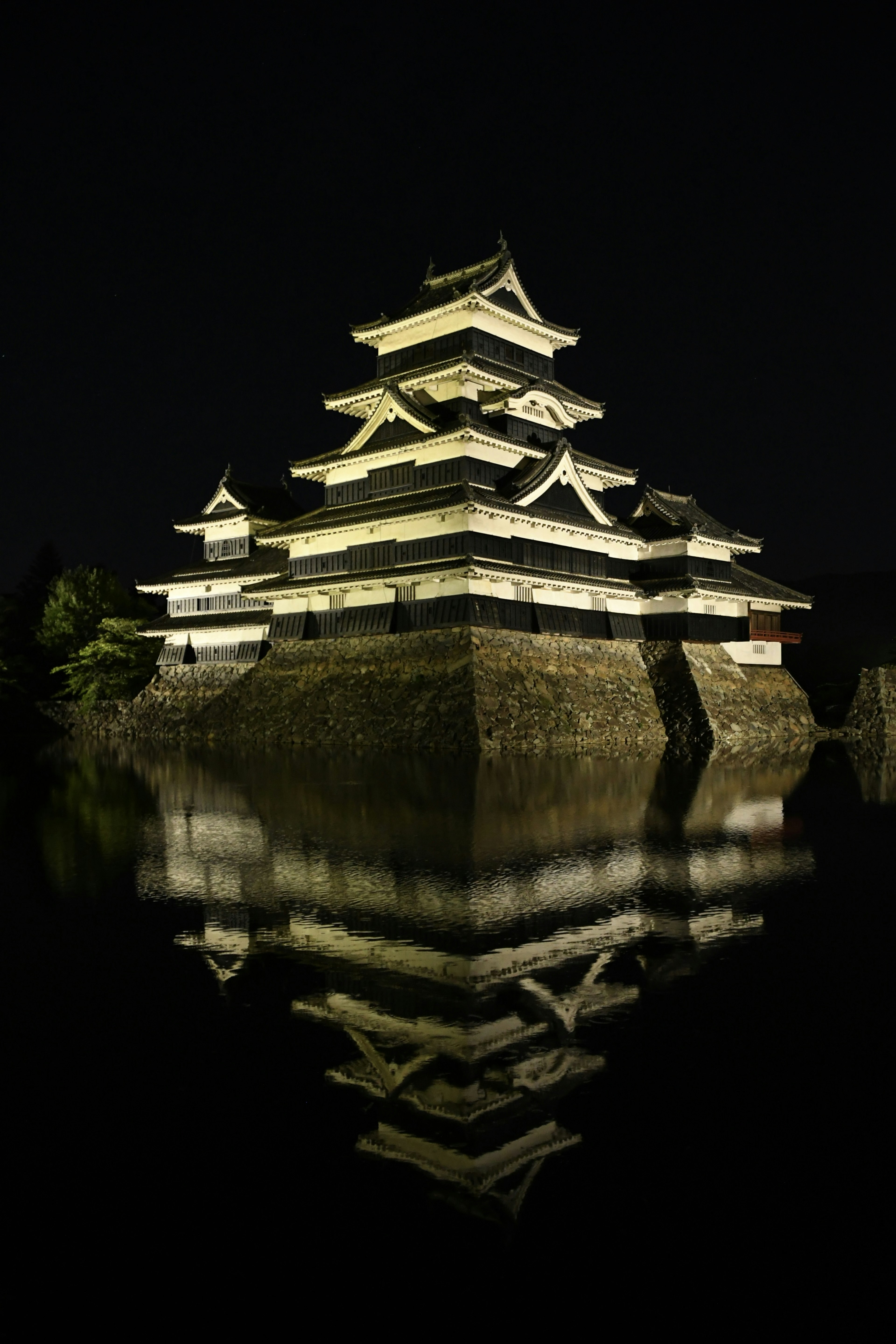 夜间照亮的松本城在水中倒影